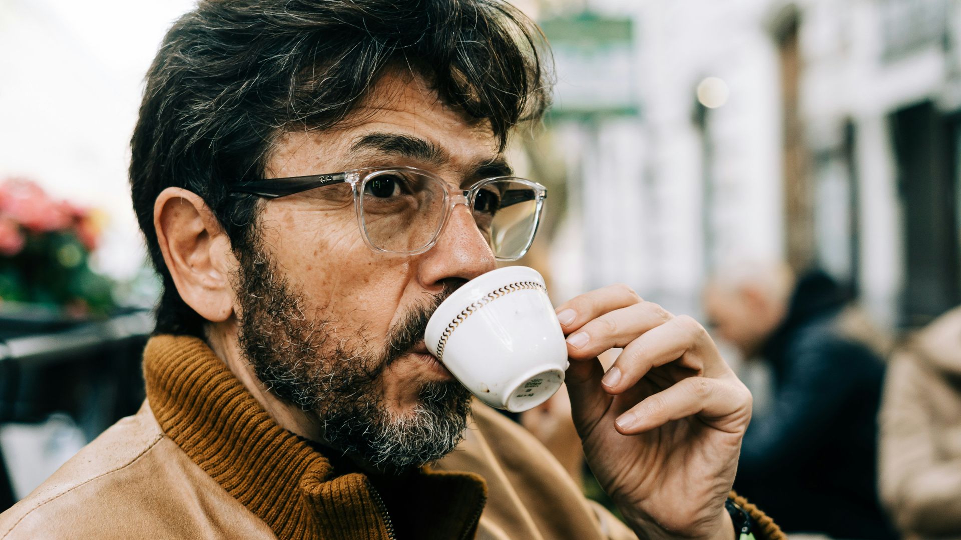 man in brown jacket drinking on white ceramic mug