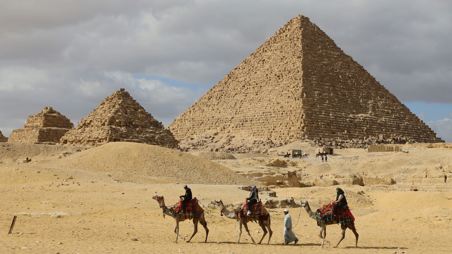 a group of people riding on the backs of camels