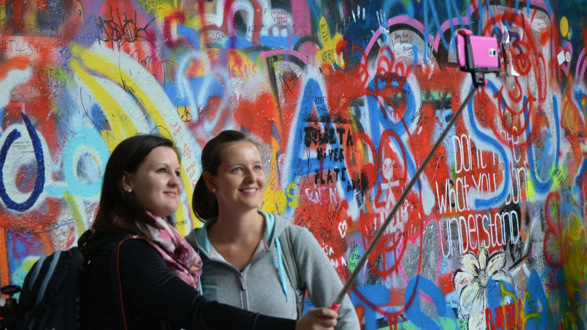woman in black and white jacket standing beside wall with graffiti