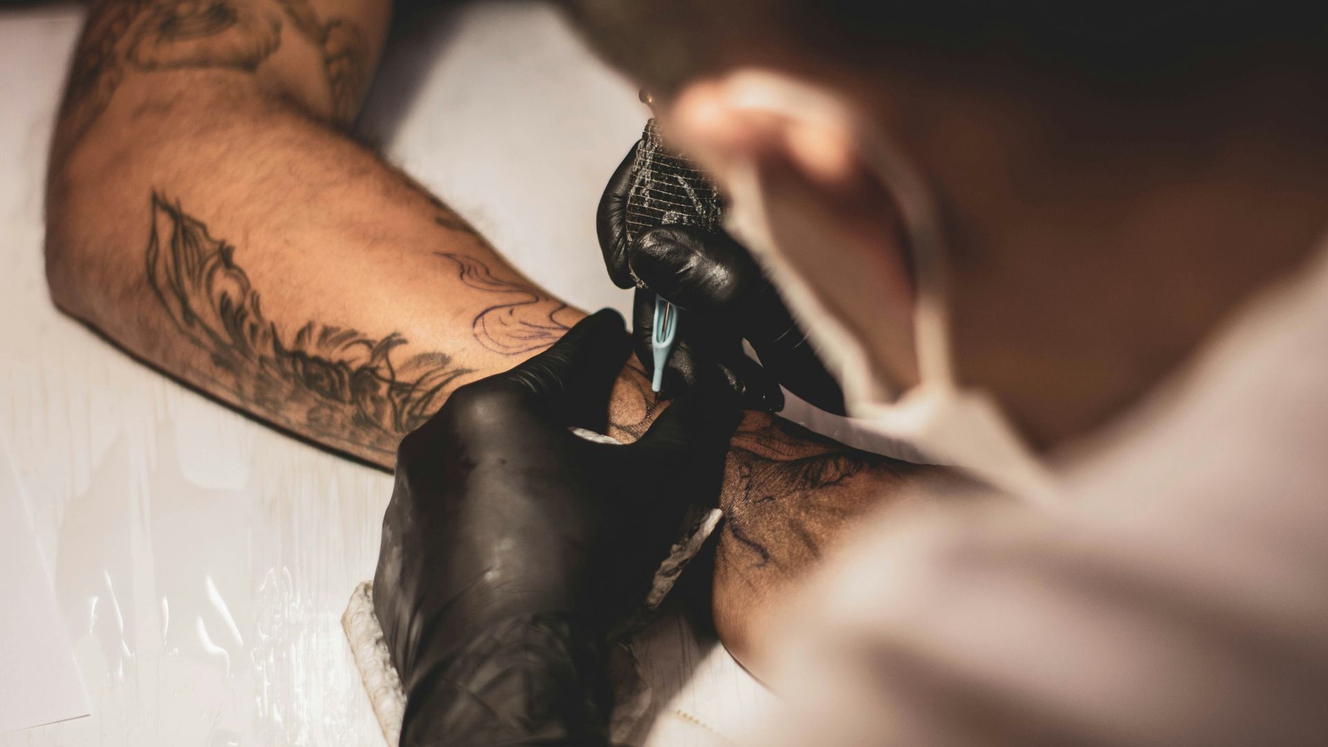 shallow focus photo of person tattooing person's right arm