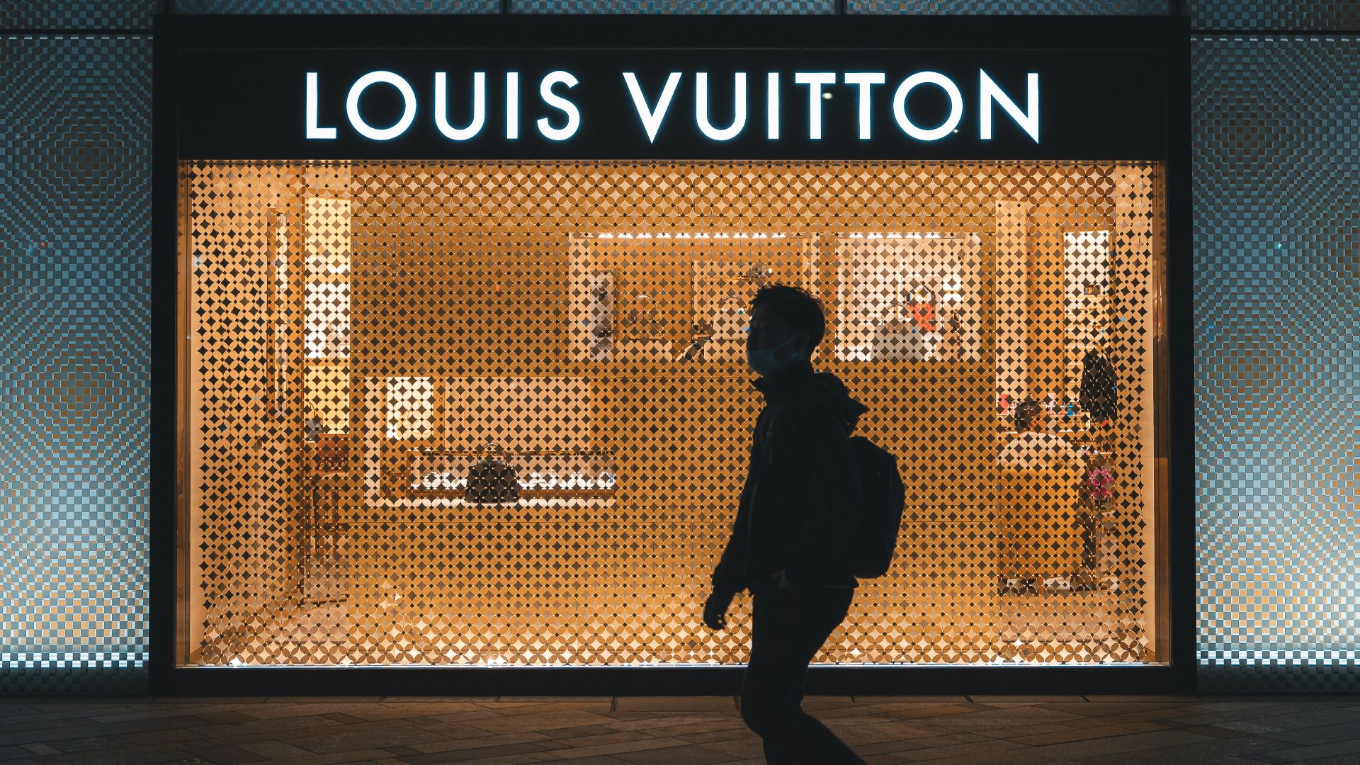 a person walking in front of a louis vuitton store