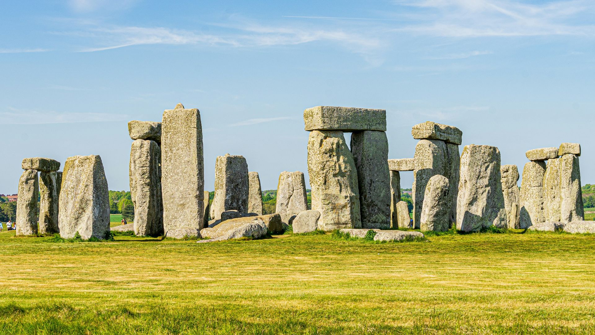 gray rock formation on green grass field under blue sky during daytime