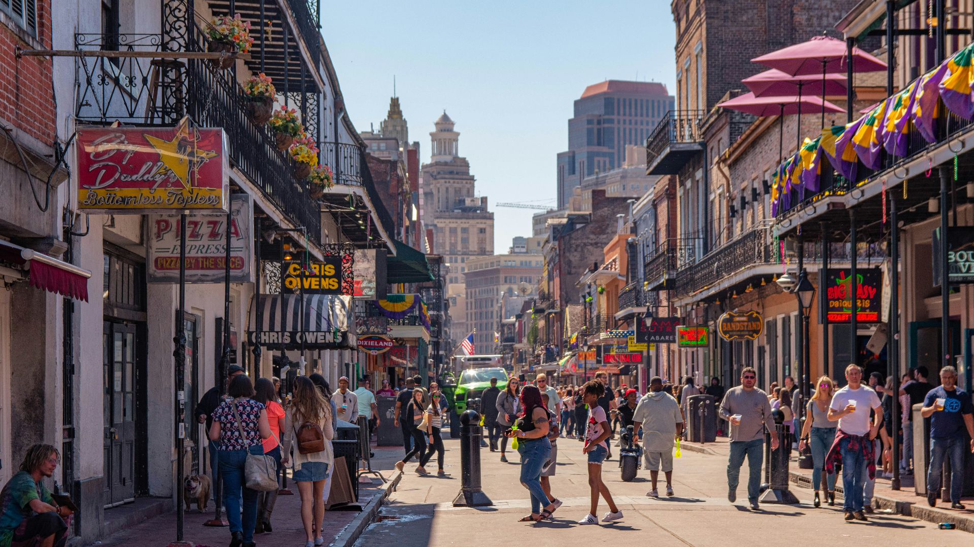 a group of people walking down a street next to tall buildings