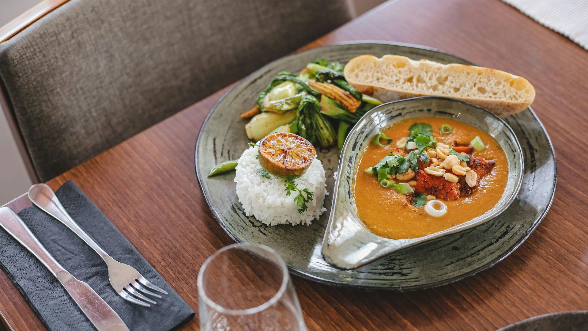 vegetable dish on white ceramic plate beside silver fork and knife on brown wooden table