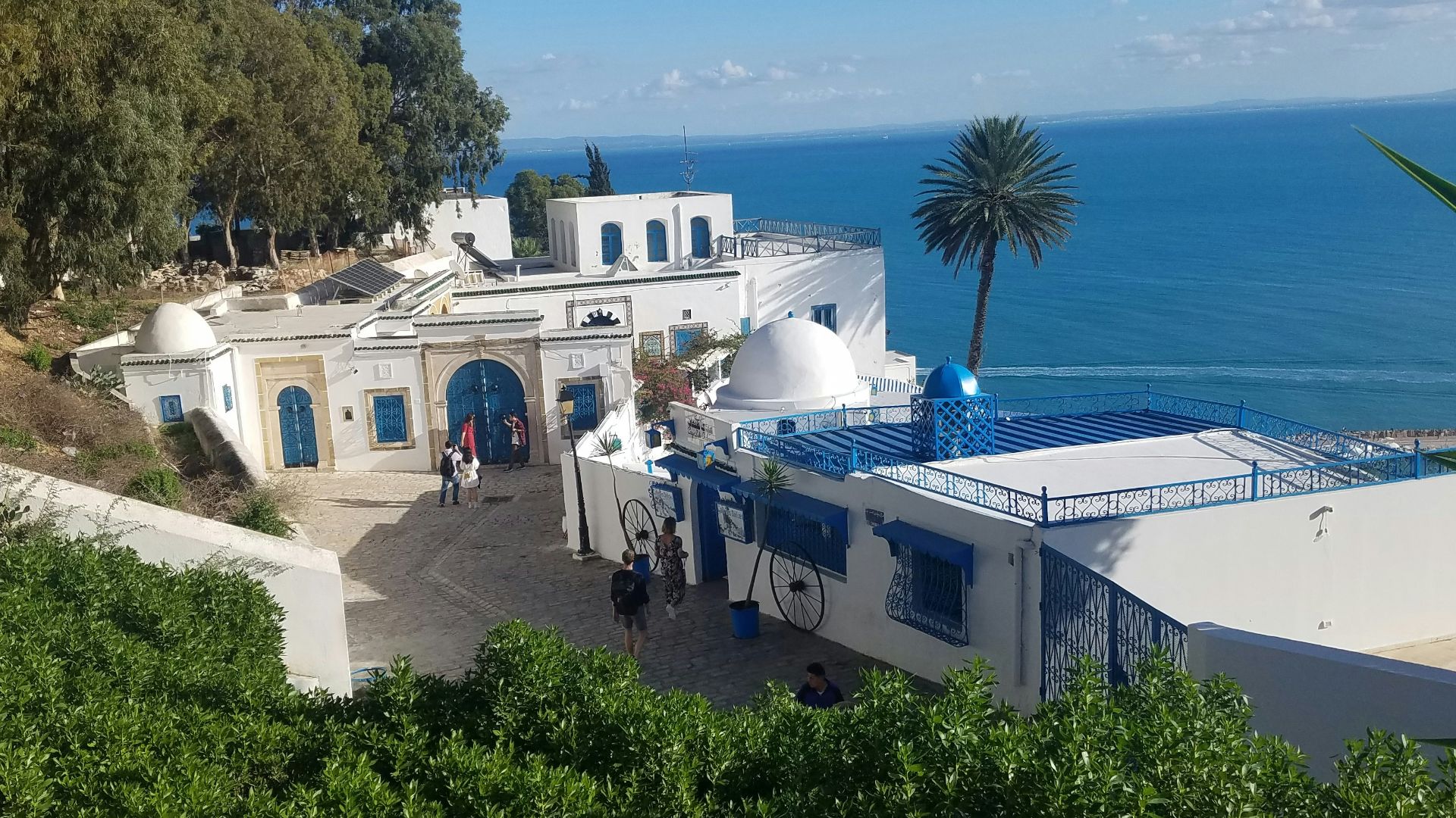 people near white and blue seaside resort viewing blue sea under blue and white sky