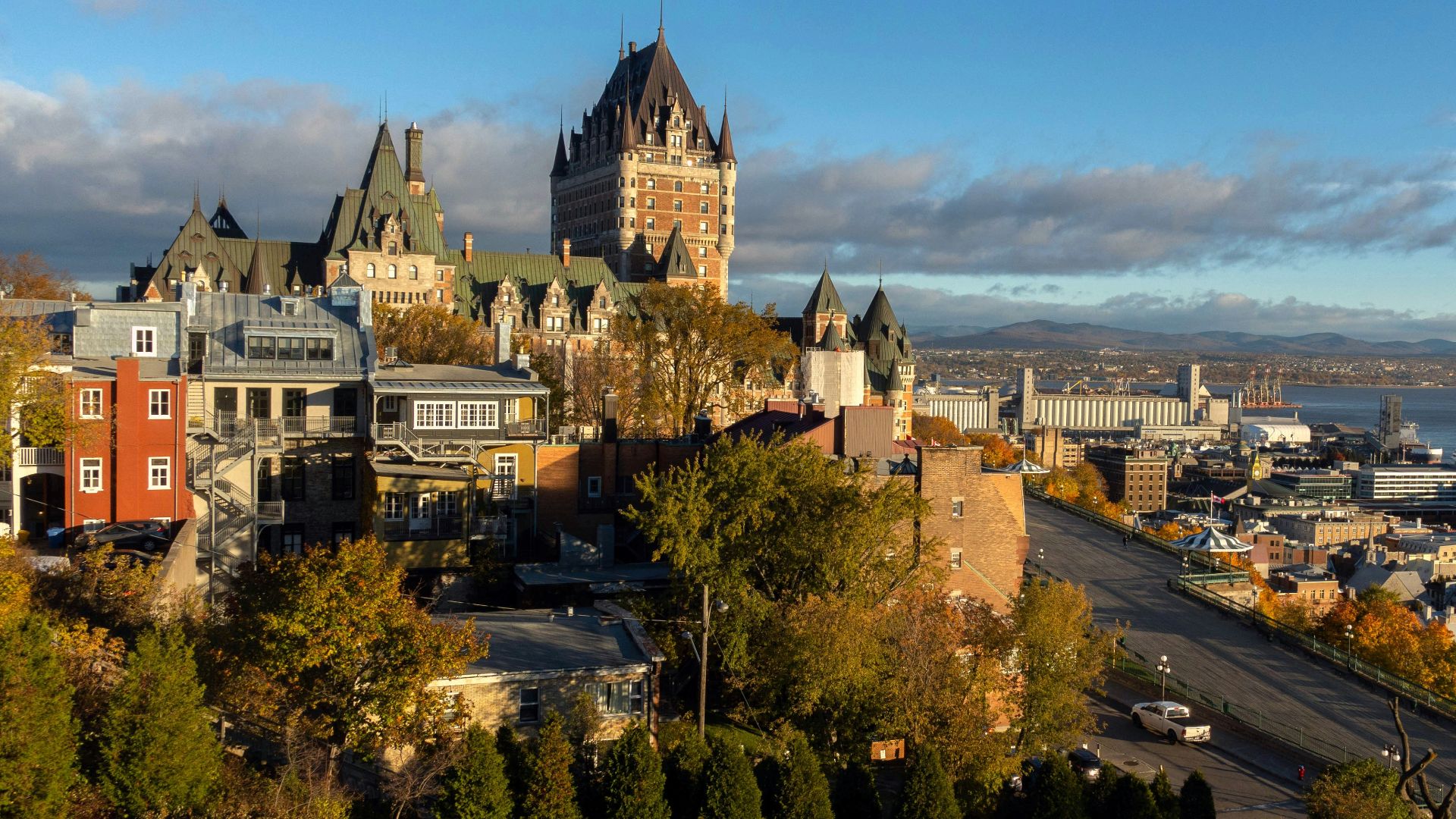 few cars on road near concrete buildings viewing sea
