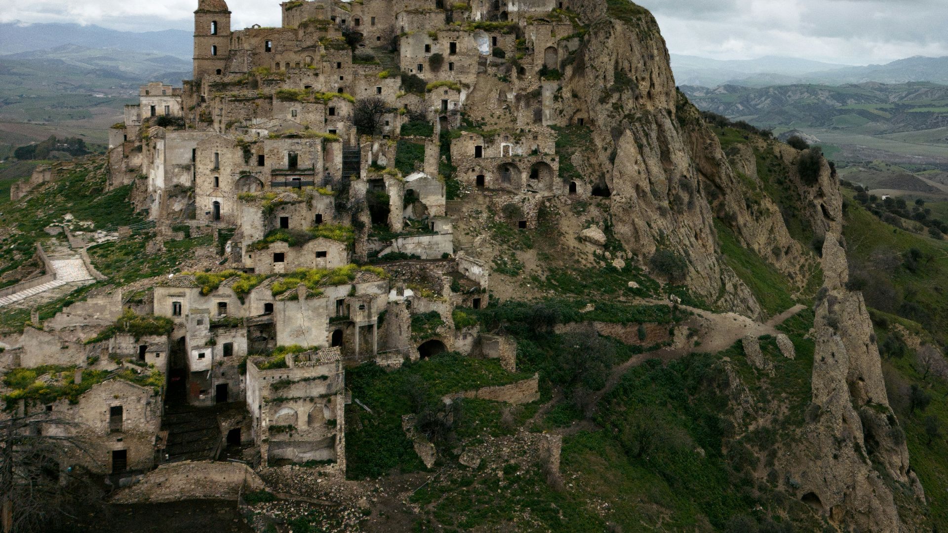 a castle perched on top of a mountain under a cloudy sky