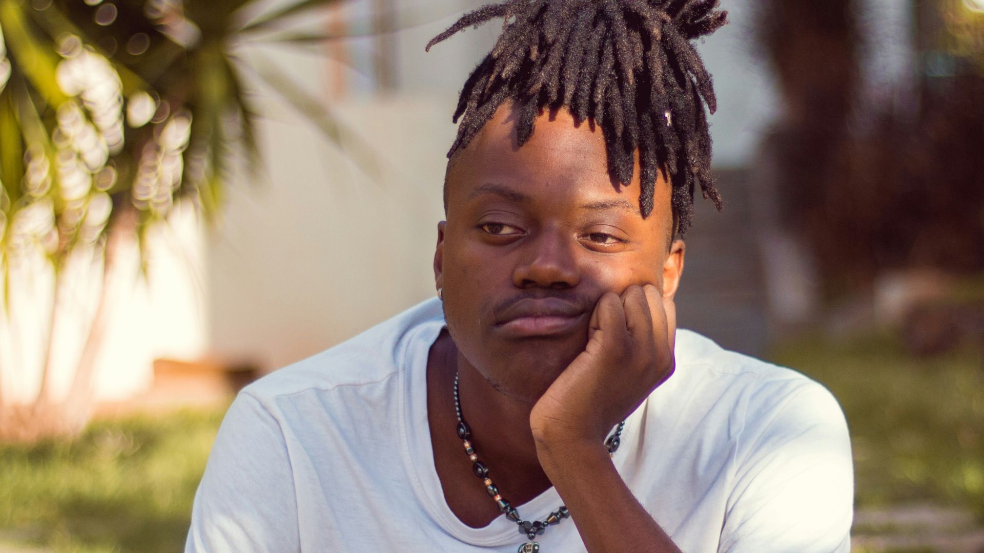 man in white crew neck t-shirt sitting on brown wooden chair