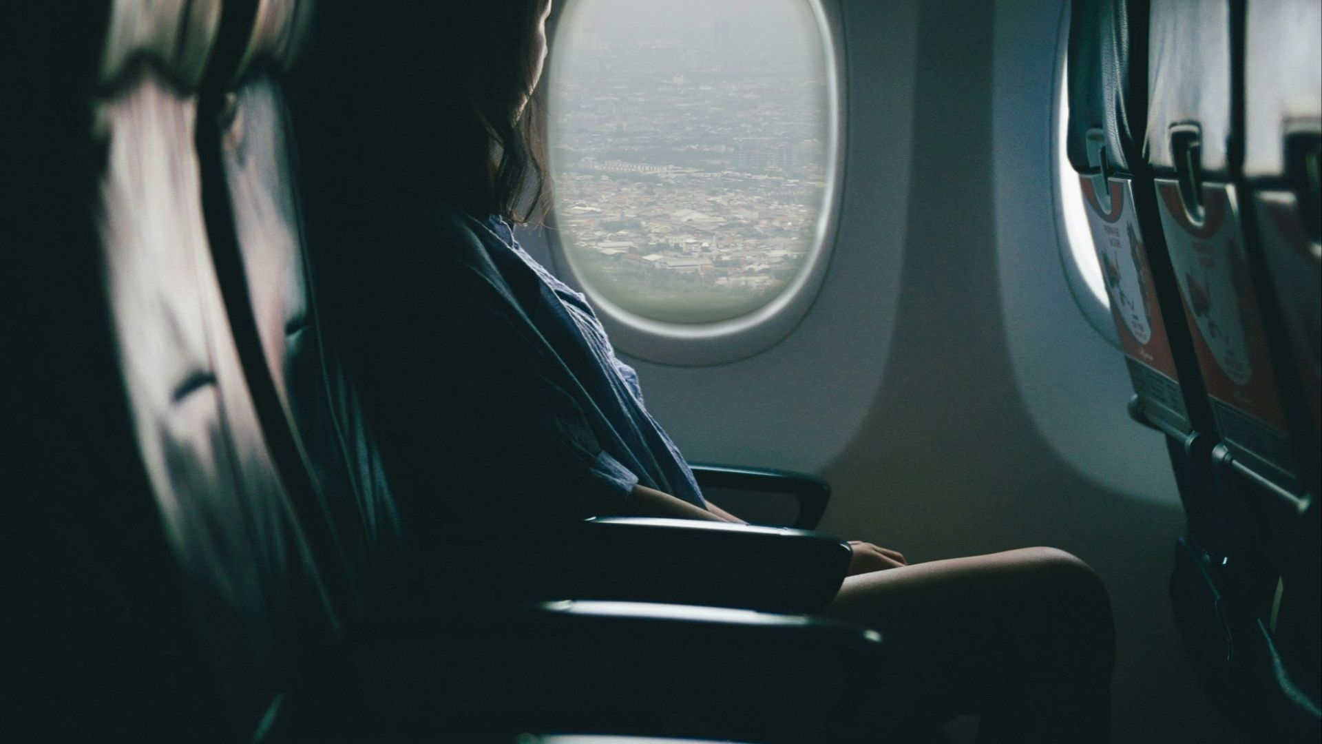 woman sits on seat near window inside plane