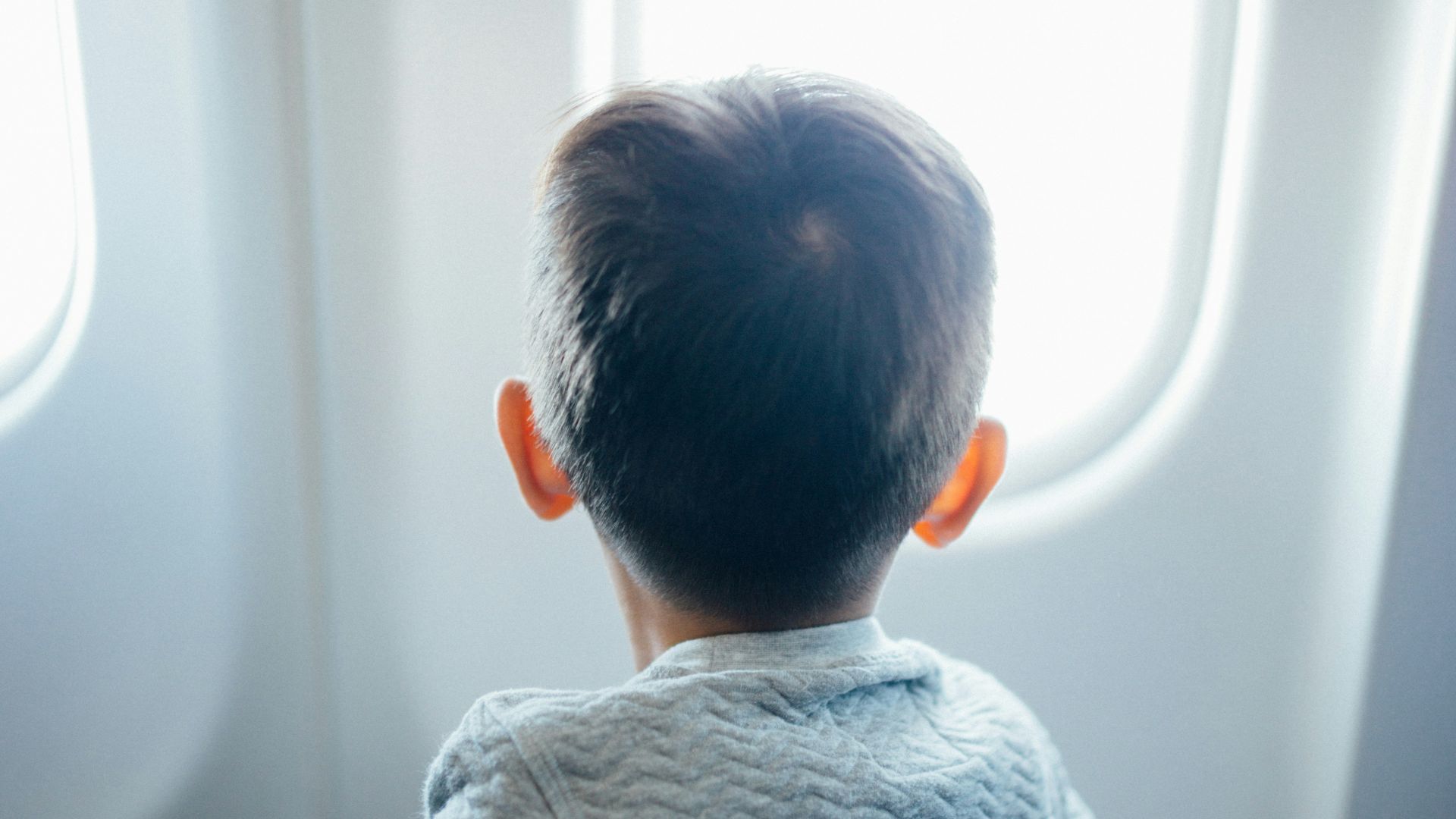 boy sitting on plane seat while viewing window