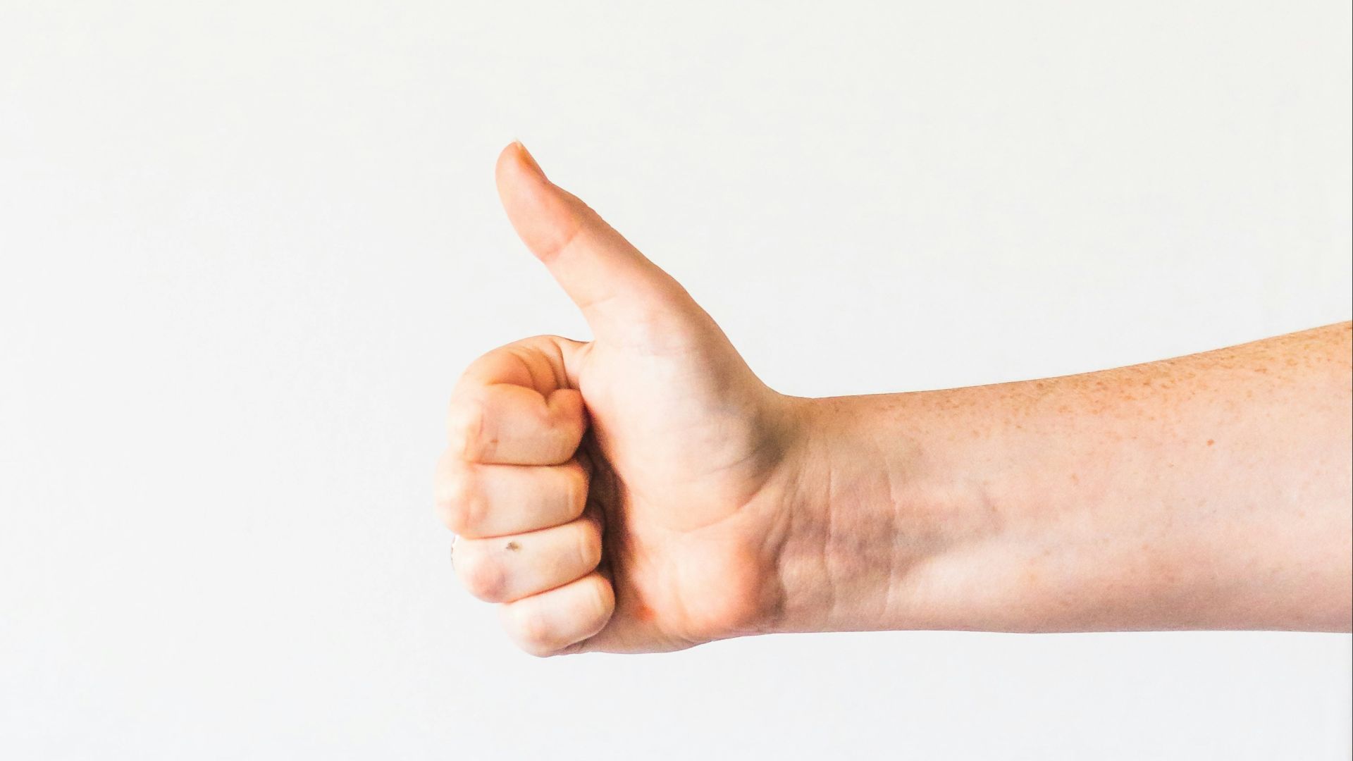 persons right hand doing thumbs up