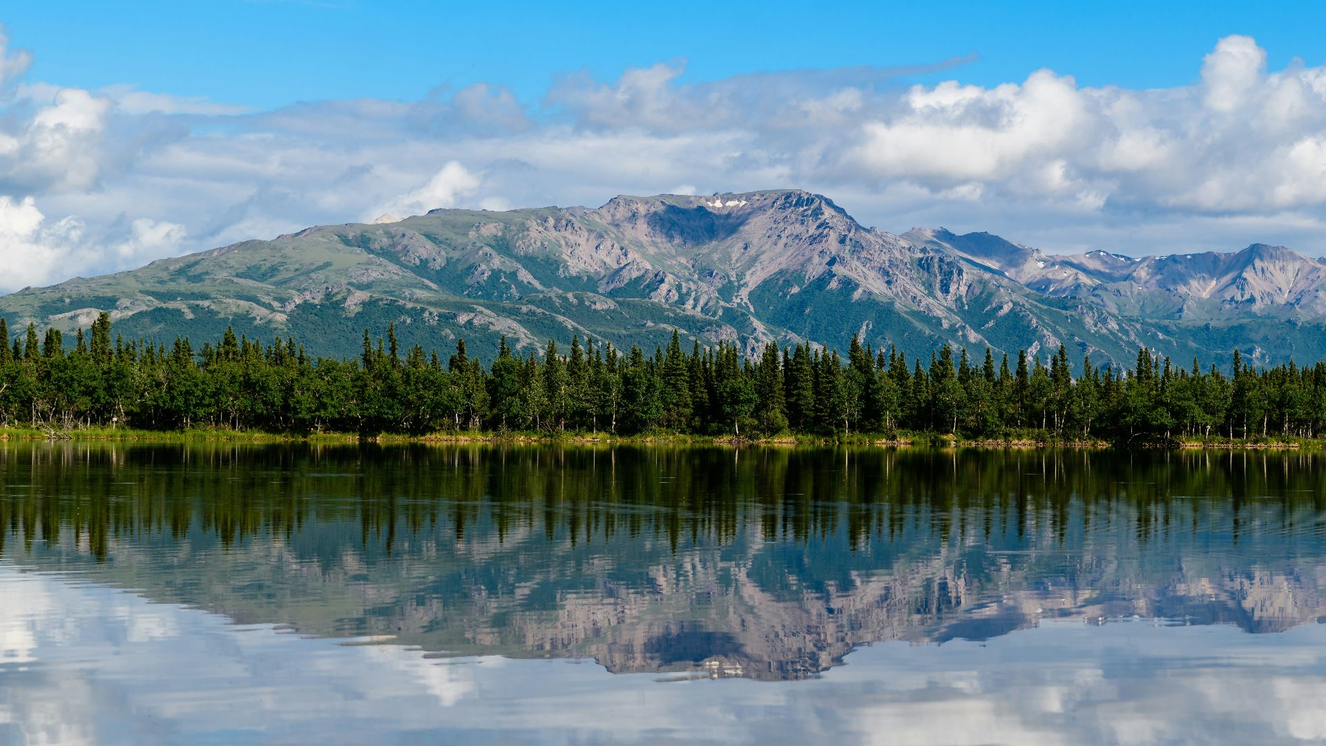 mountain and blue body of water under cloudy sky