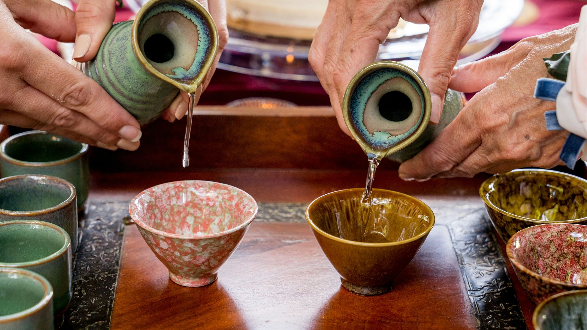 a group of people pouring liquid into small cups