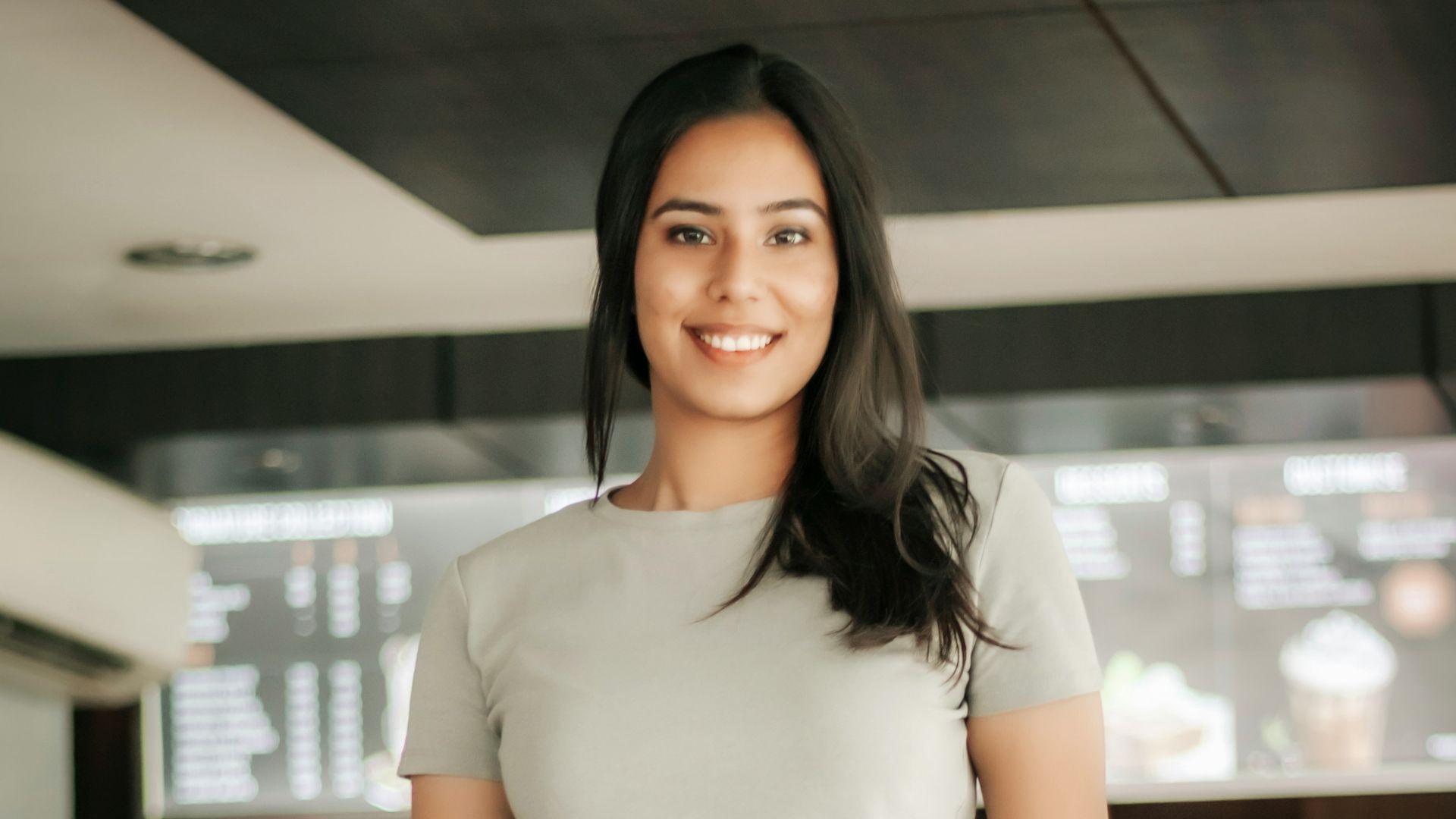 woman in white shirt and green pants standing near black chair