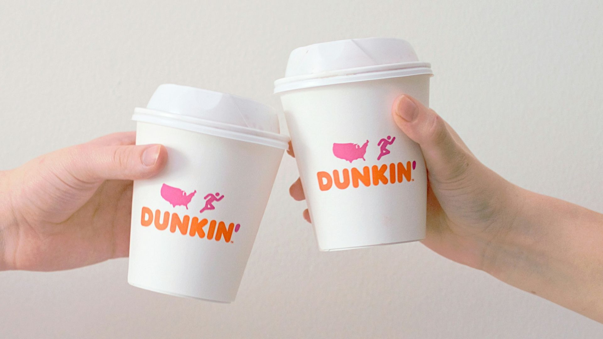 two people with white Dunkin' Donuts paper cups