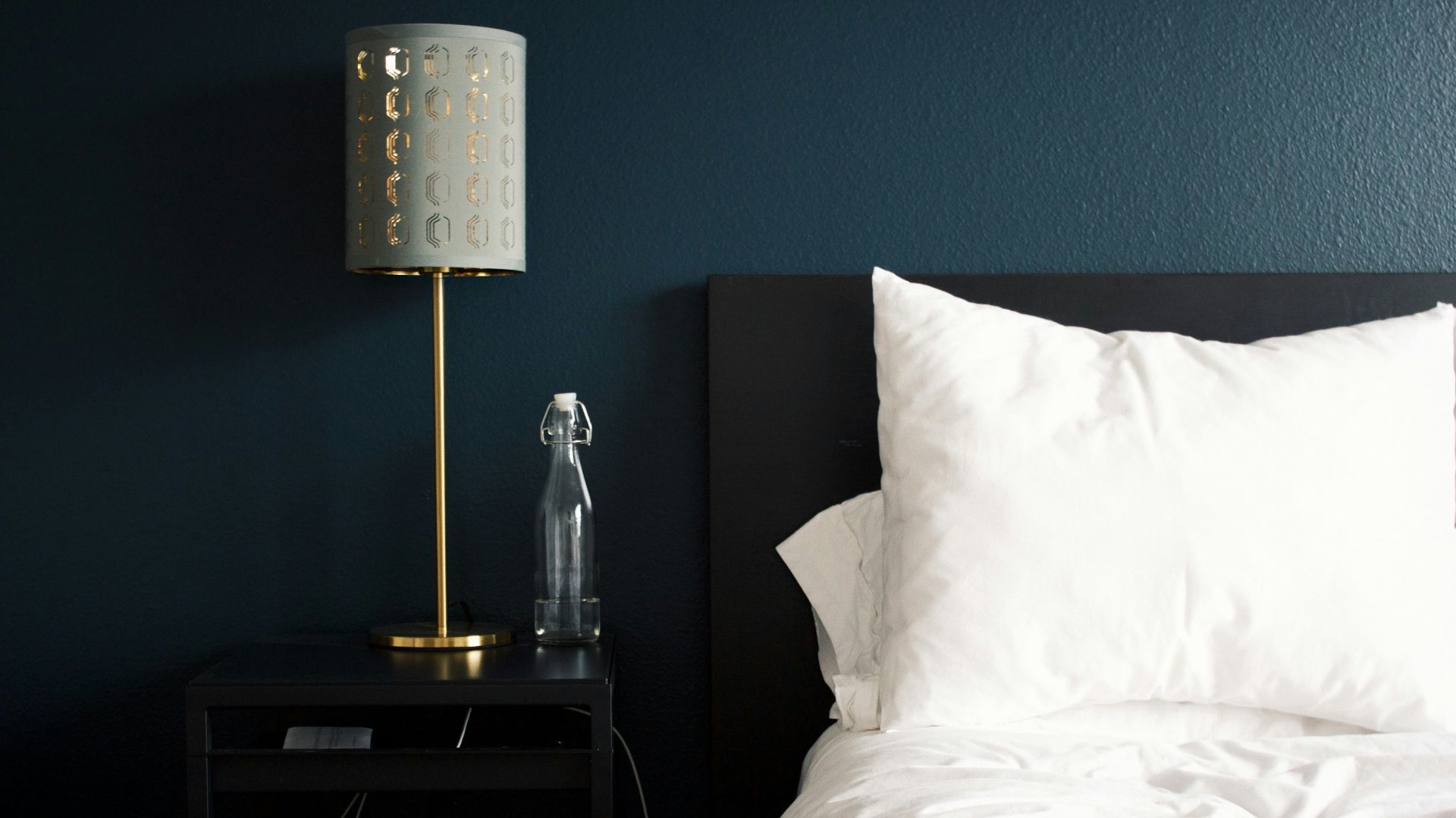 gray table lamp beside white bed pillow