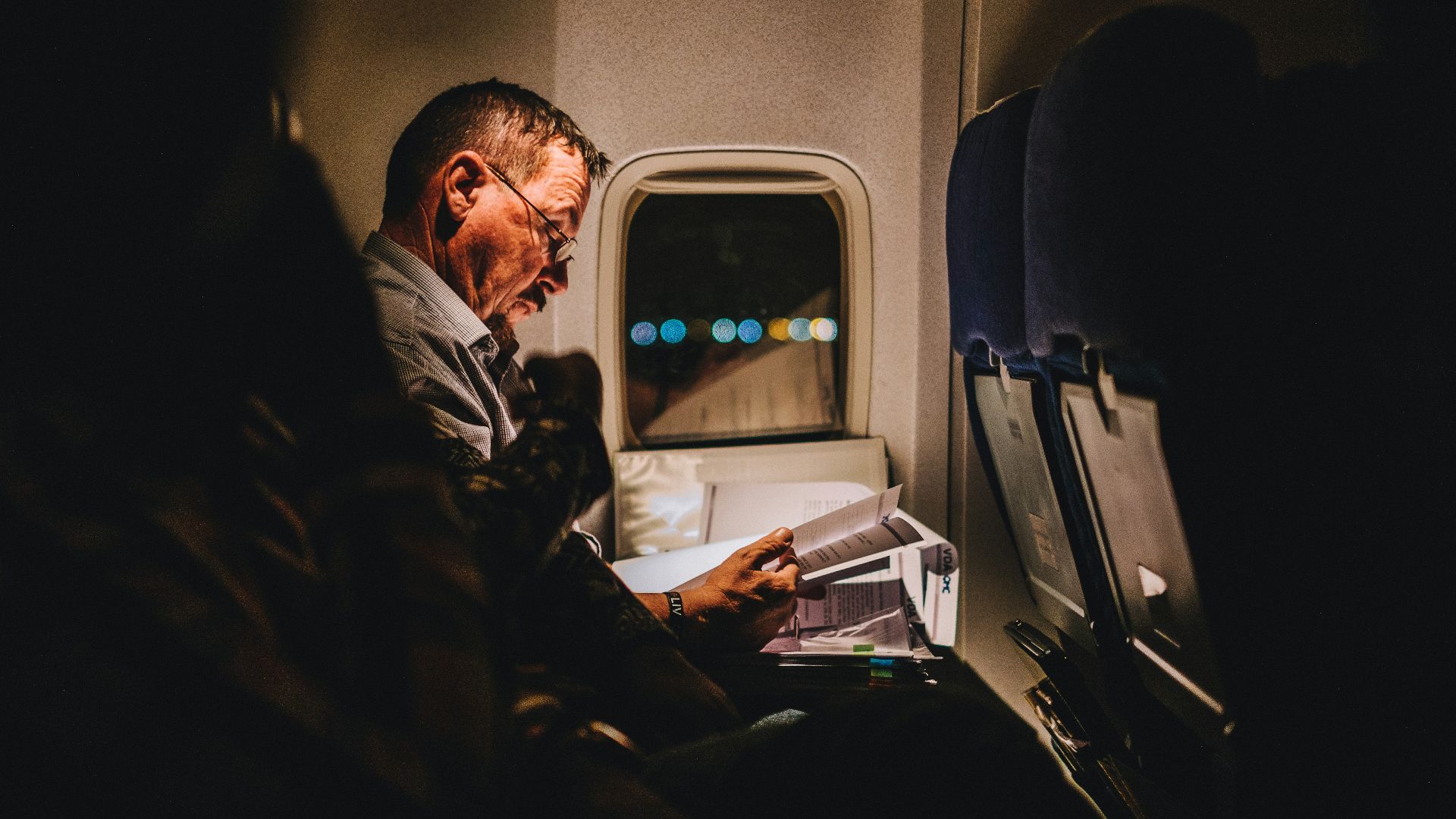 man reading book inside vehicle