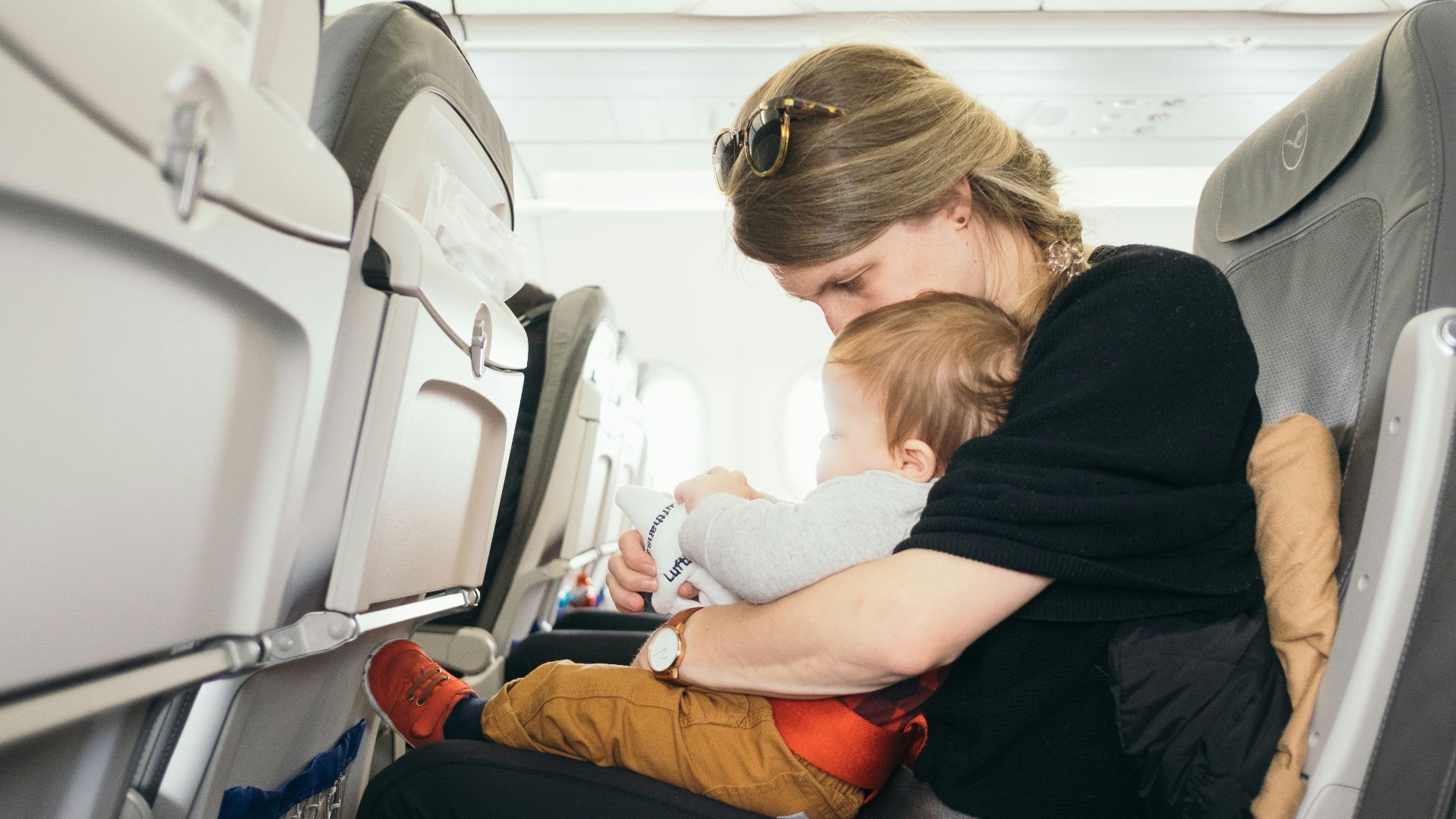 woman carrying baby while sitting on gray seat