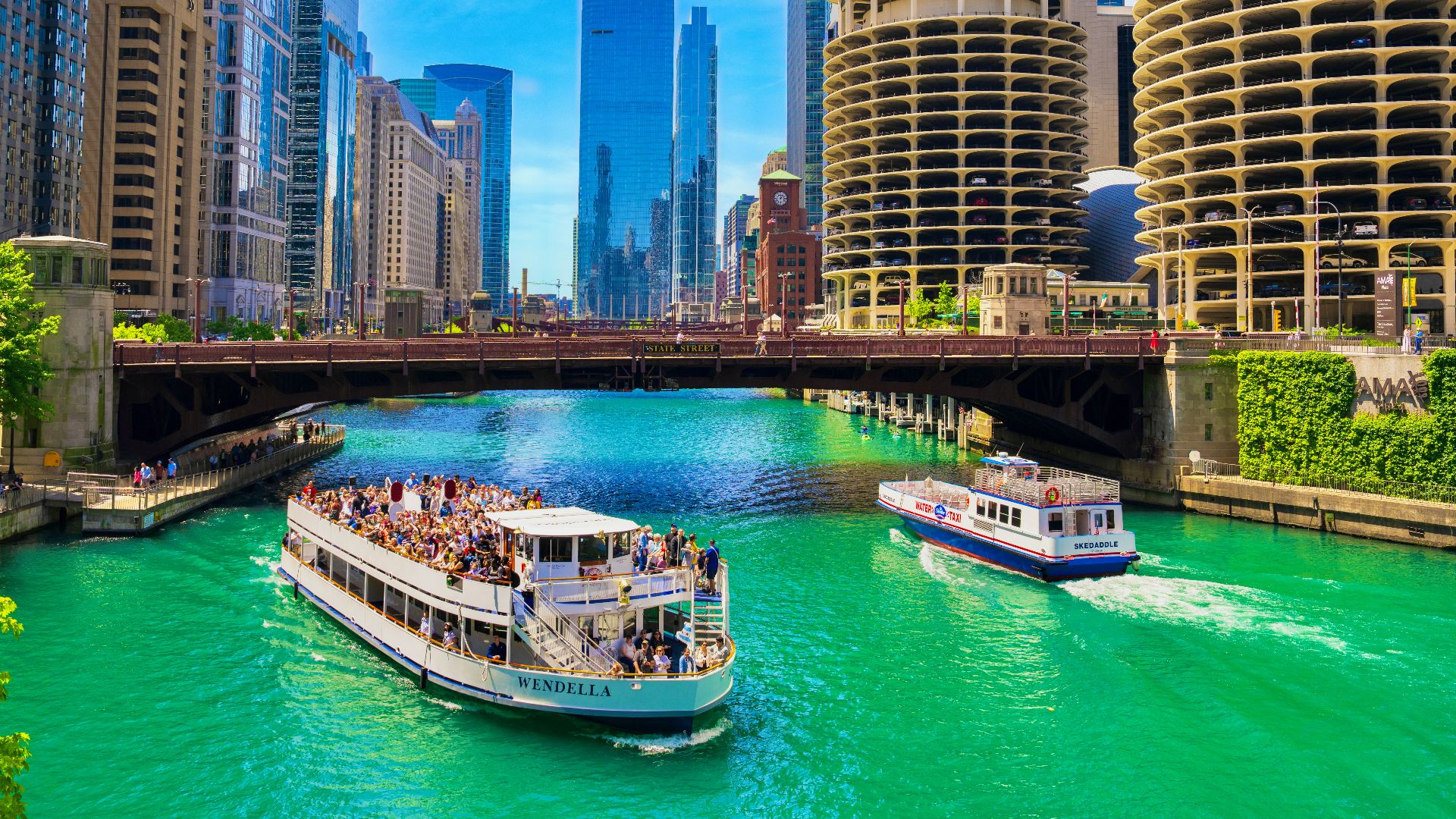 A river filled with lots of green water next to tall buildings