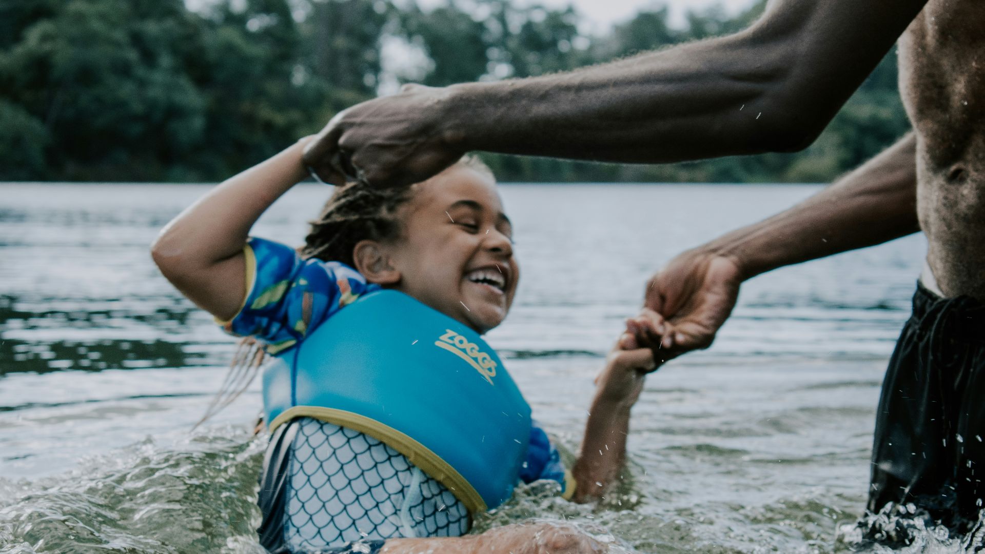 girl in blue and yellow tank top playing on water during daytime