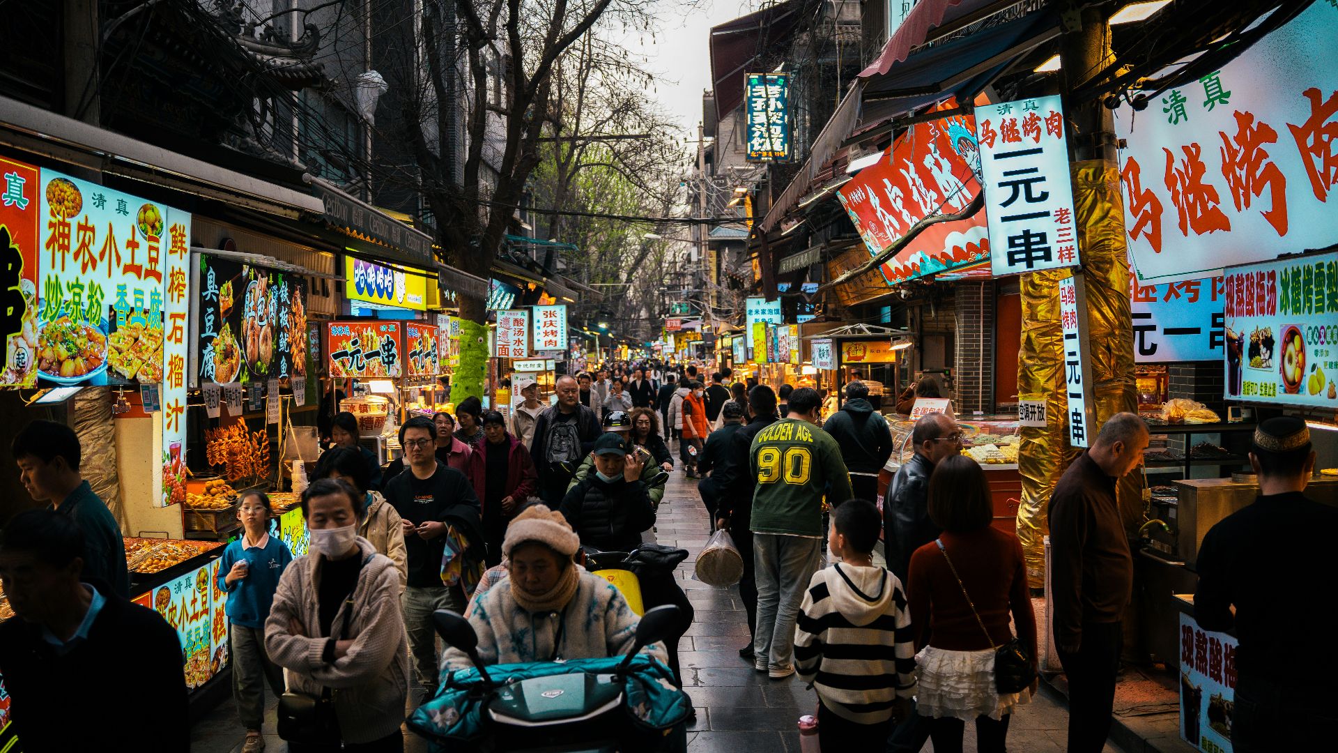 A bustling asian street market is filled with people.