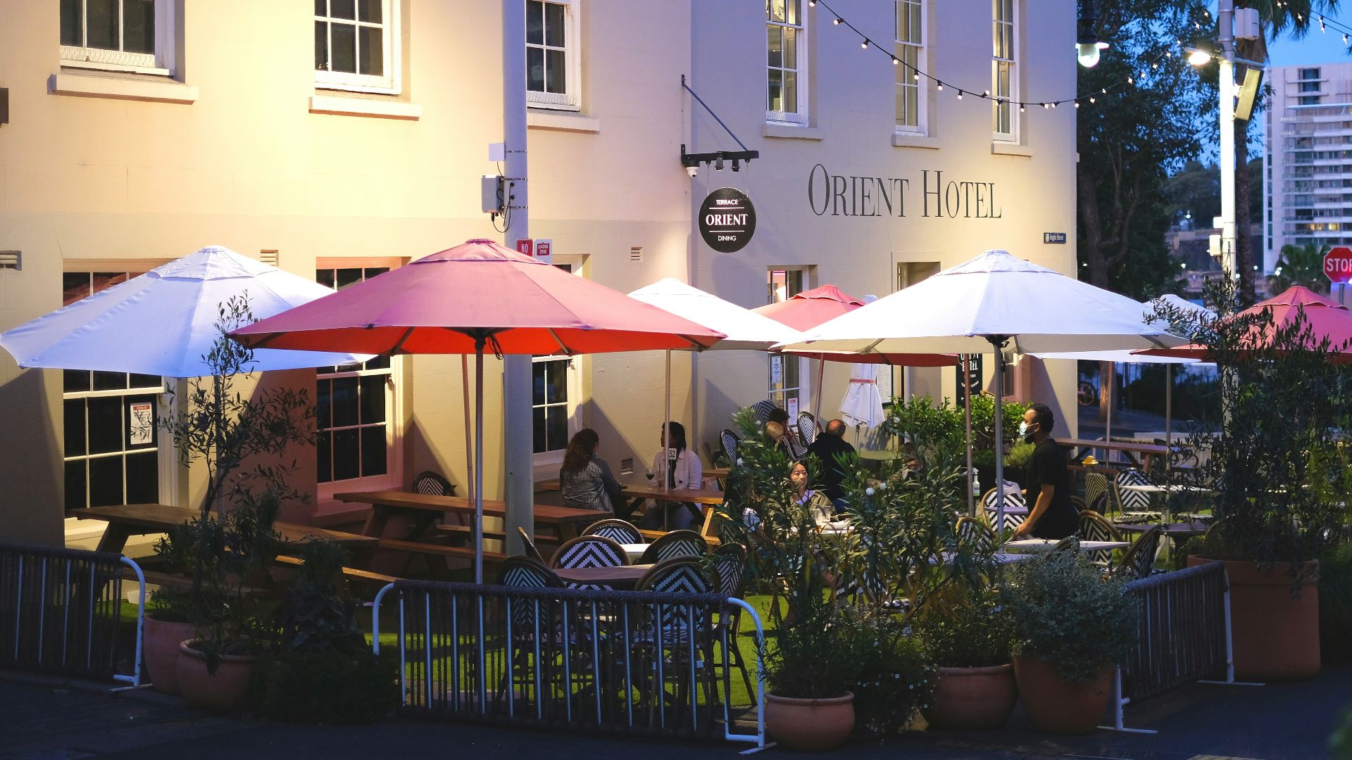a group of people sitting at tables under umbrellas