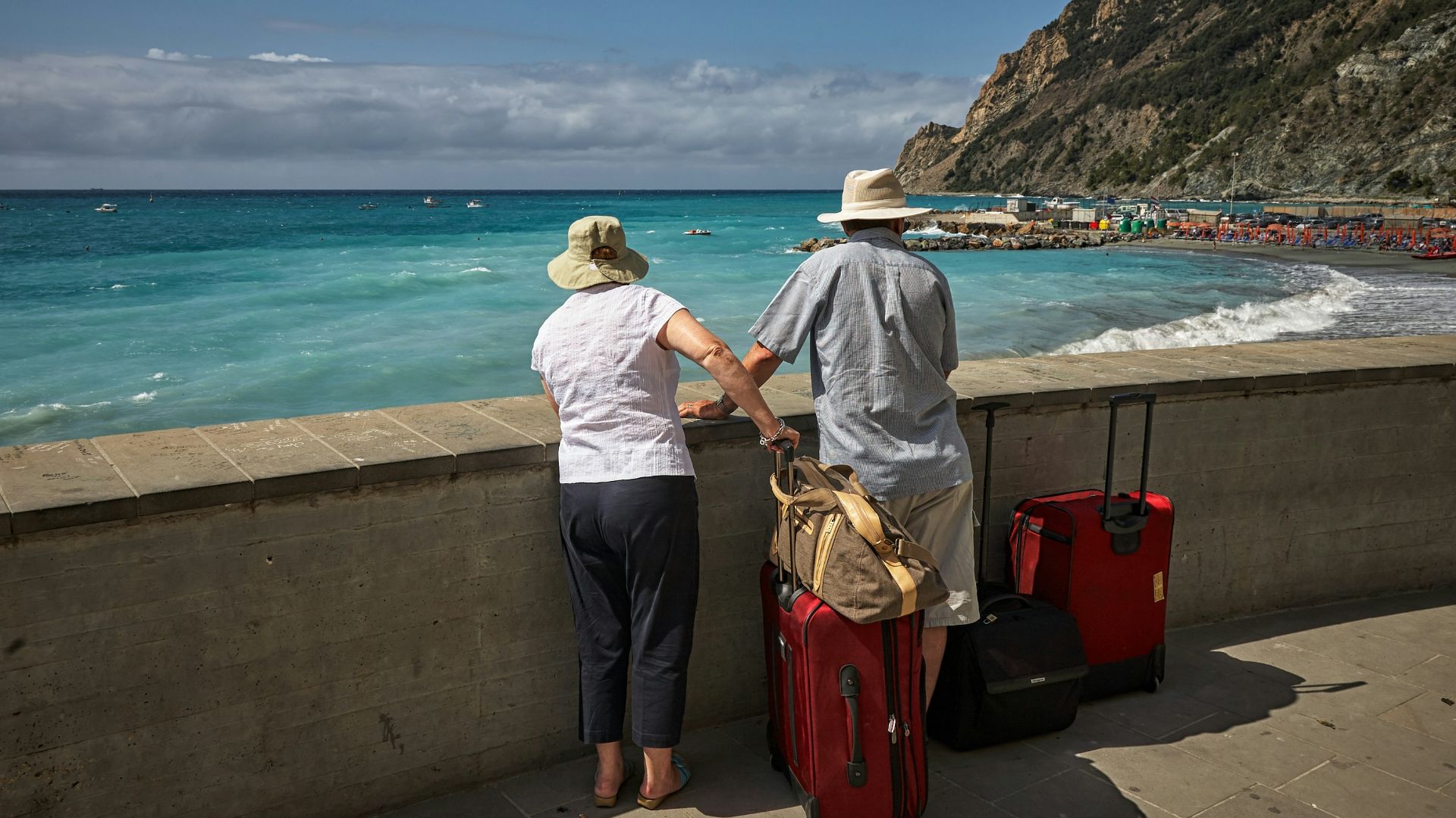 man and woman standing beside concrete seawall looking at beach