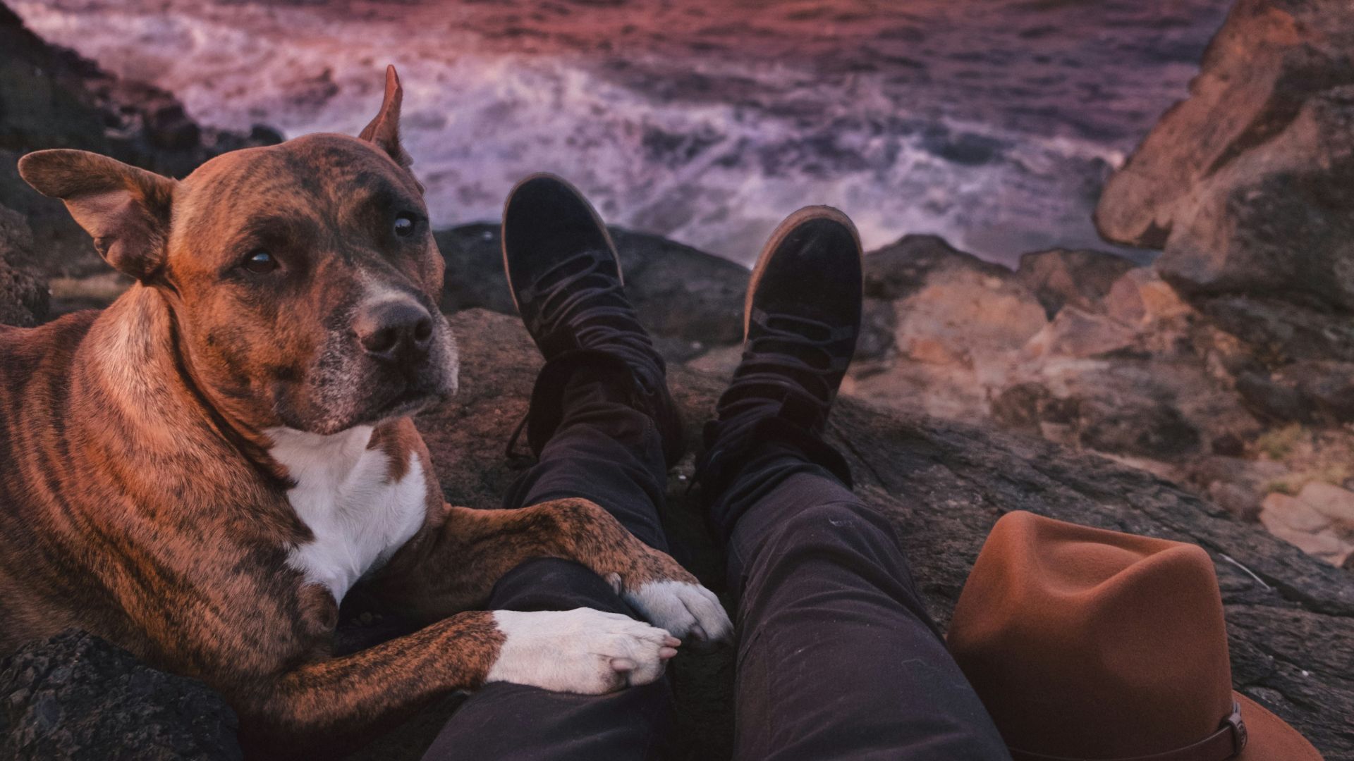 person sitting on rock beside of brindle through sea waves crashing on rock