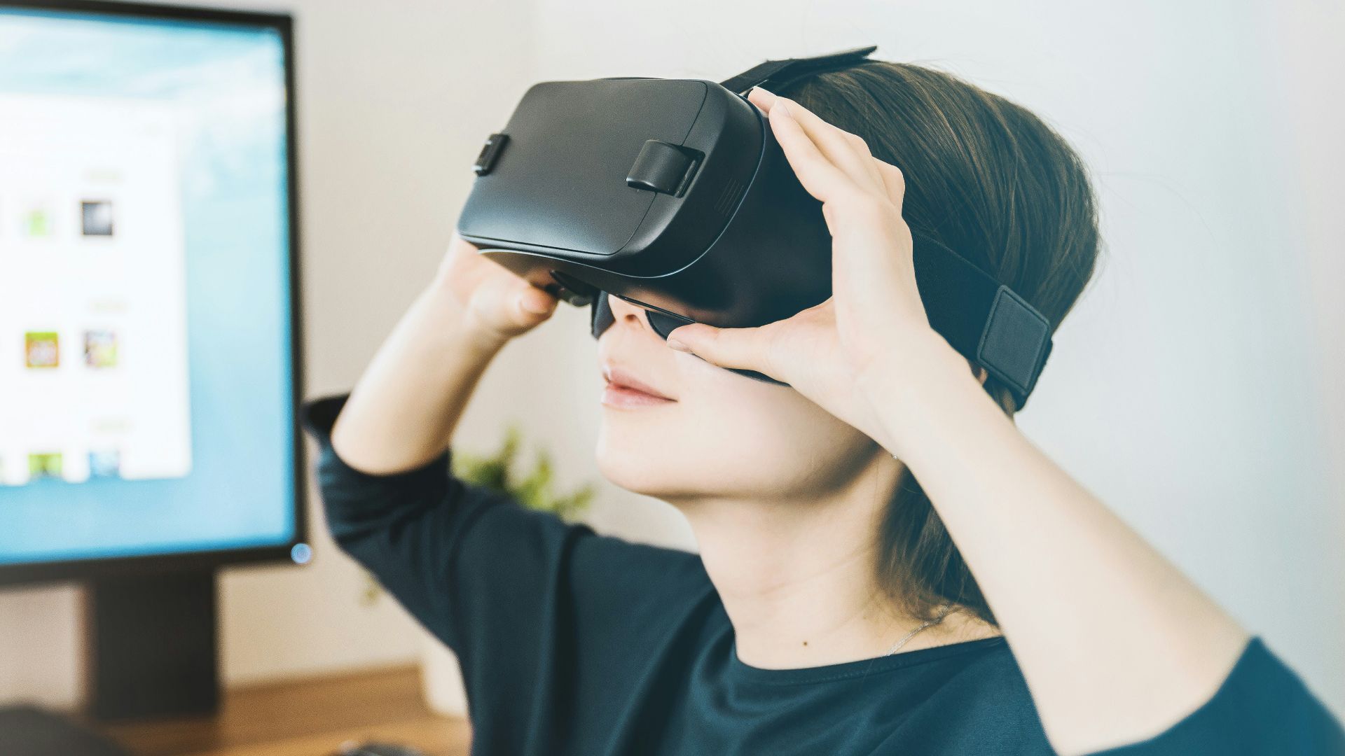 woman using black VR headset beside computer