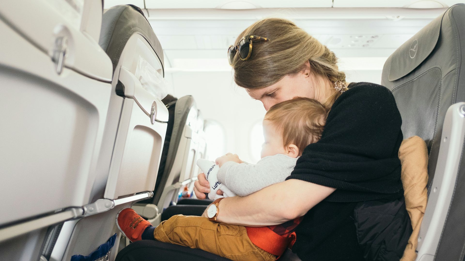 woman carrying baby while sitting on gray seat
