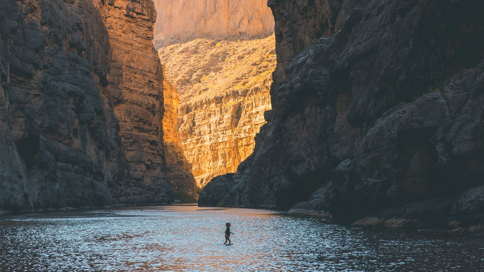 people riding boat on sea near brown rocky mountain during daytime