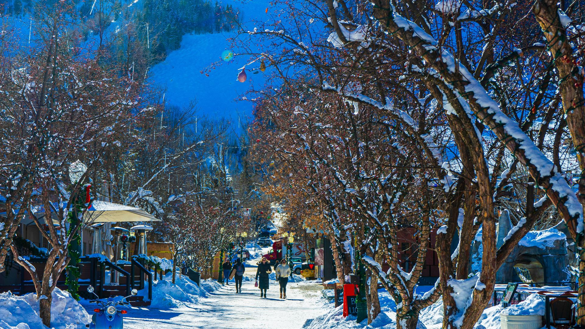 a snowy street with people walking down it