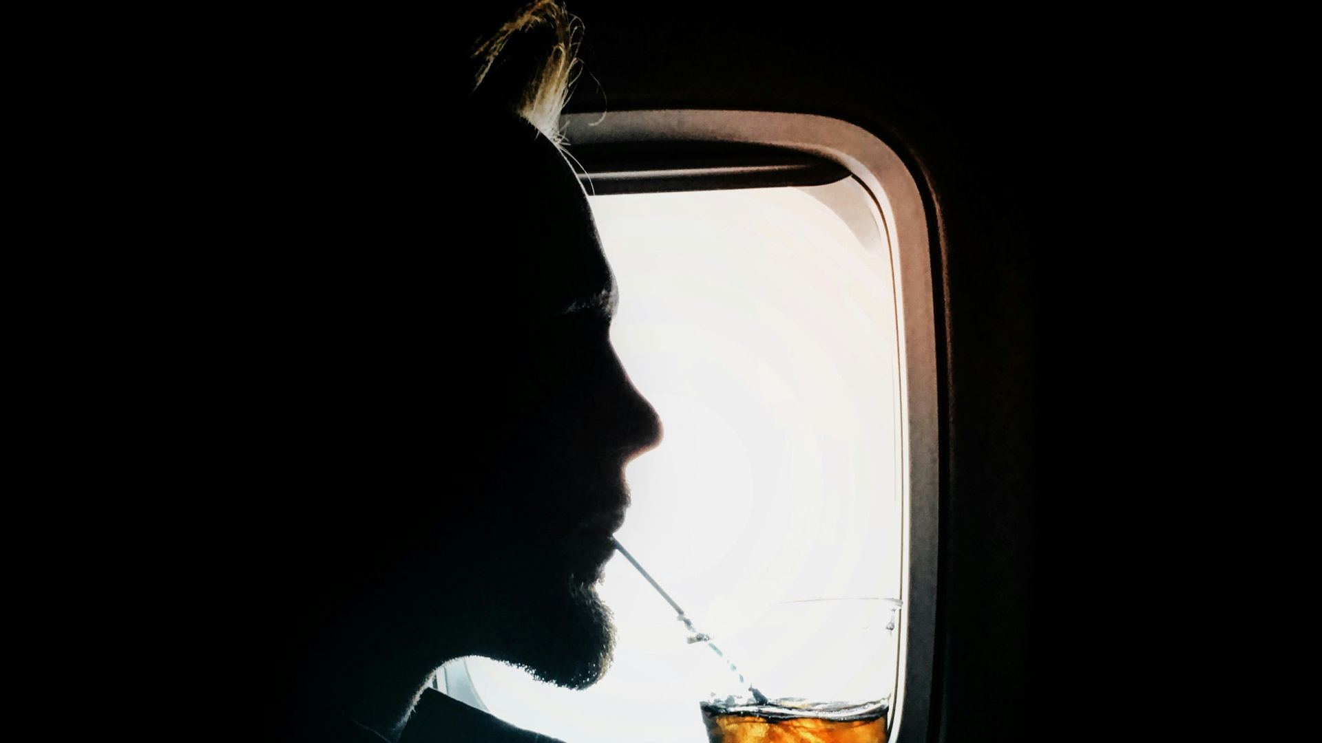 man sipping drink beside window