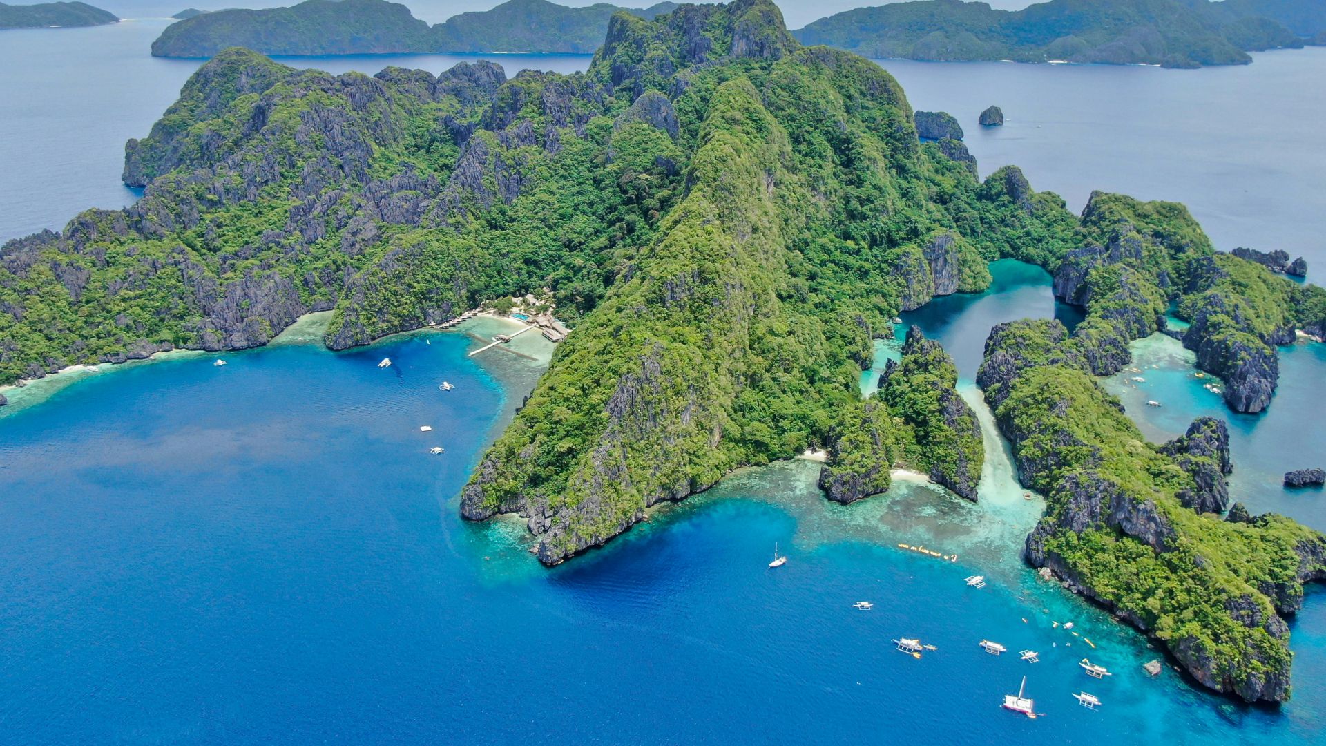 green and brown mountain beside blue sea during daytime