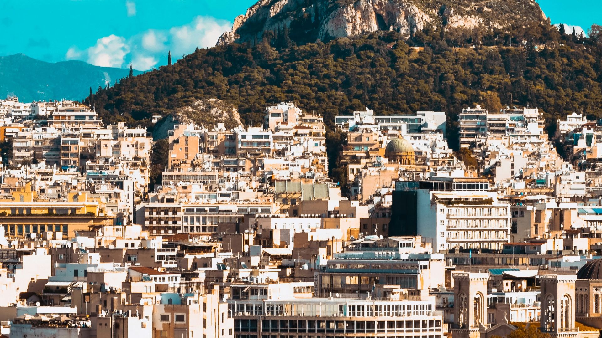 city buildings near mountain under blue sky during daytime