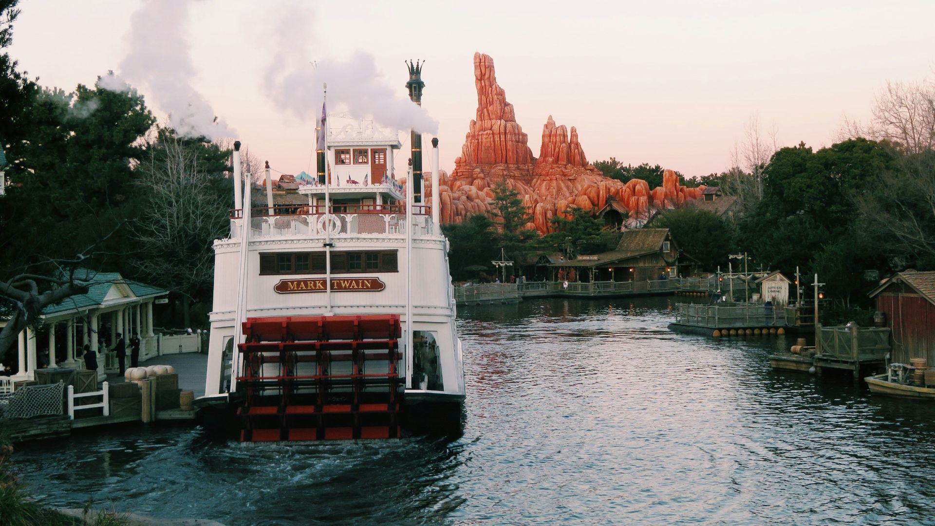 a large boat traveling down a river next to a forest