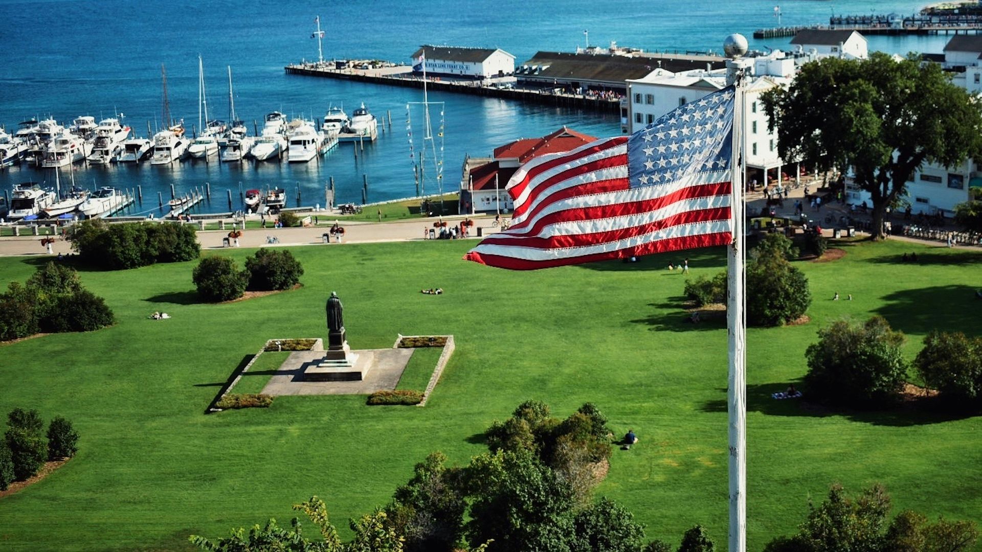 us a flag on green grass field near body of water during daytime
