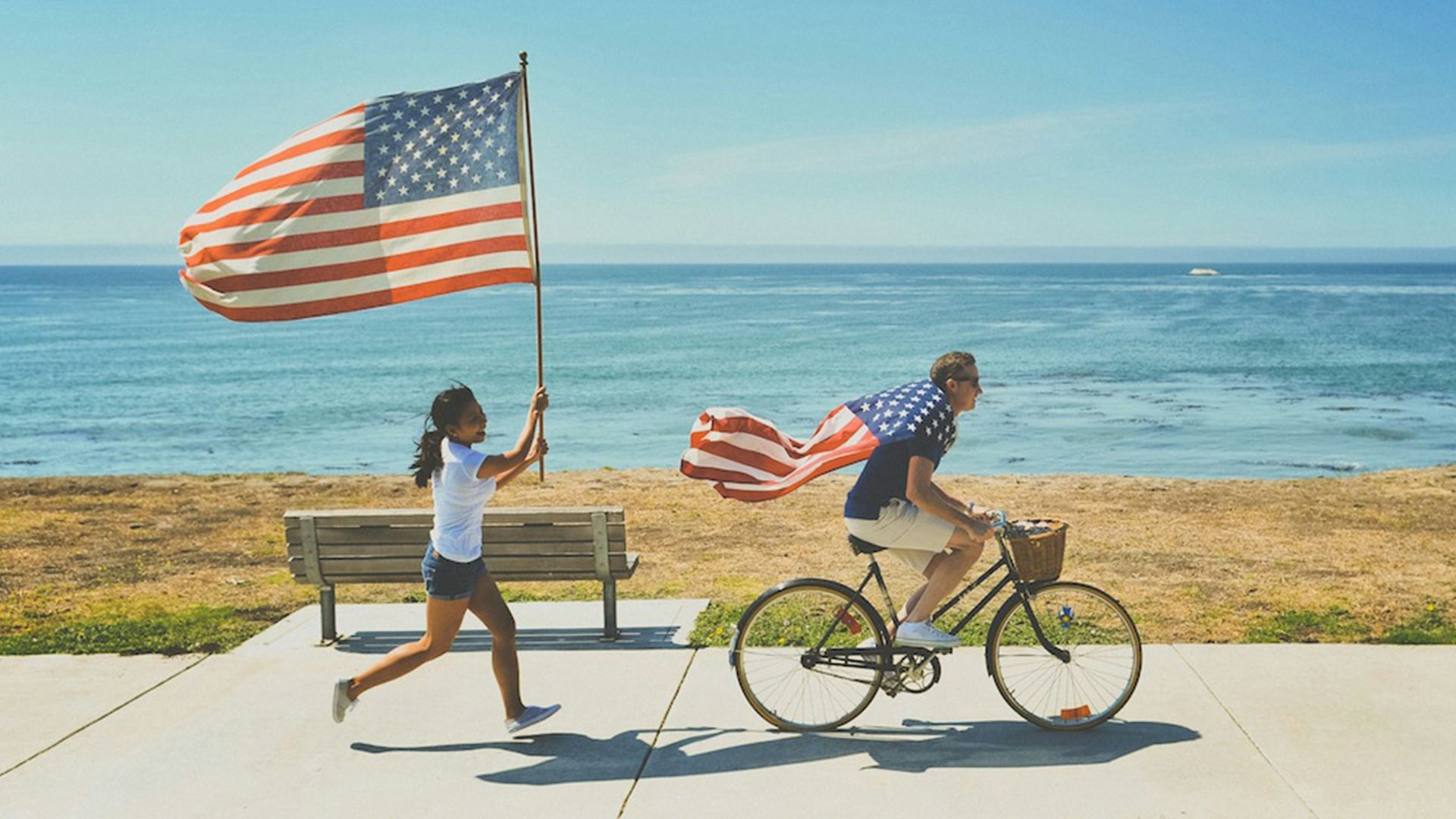 man riding bike and woman running holding flag of USA