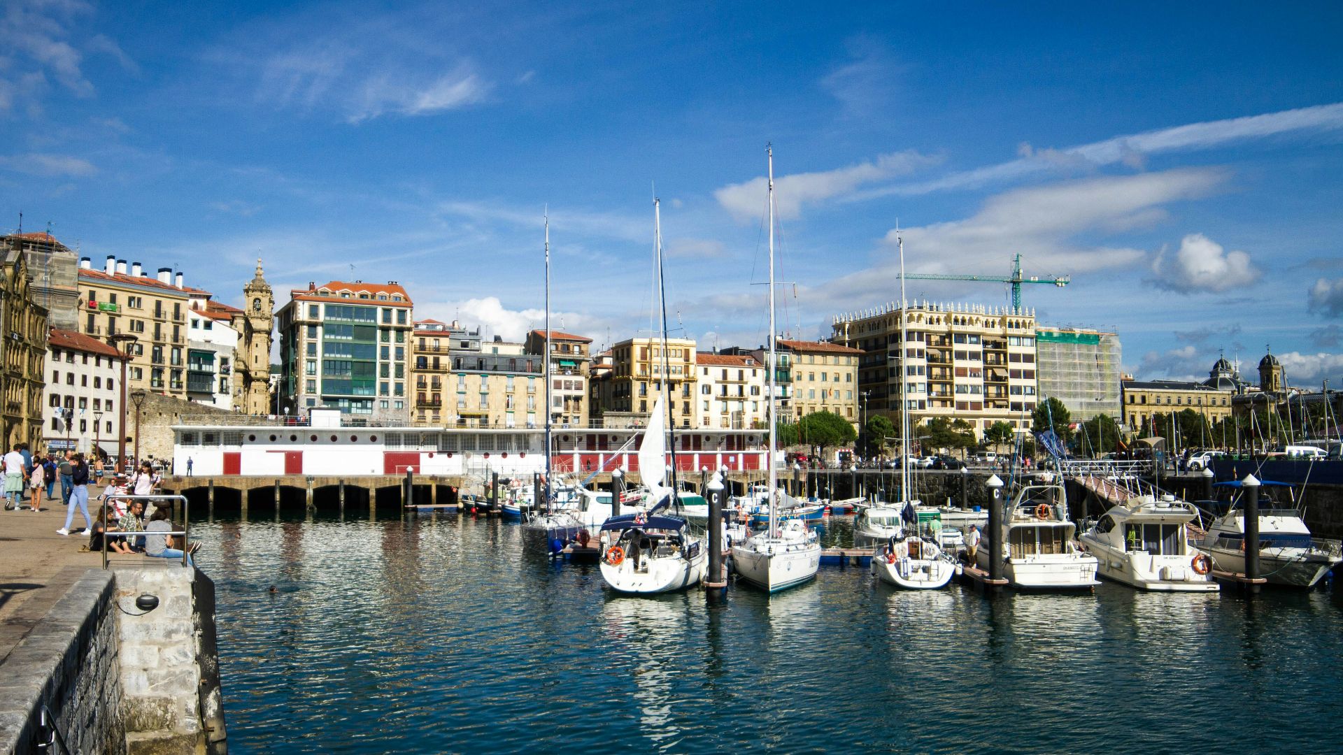 a harbor filled with lots of boats next to tall buildings