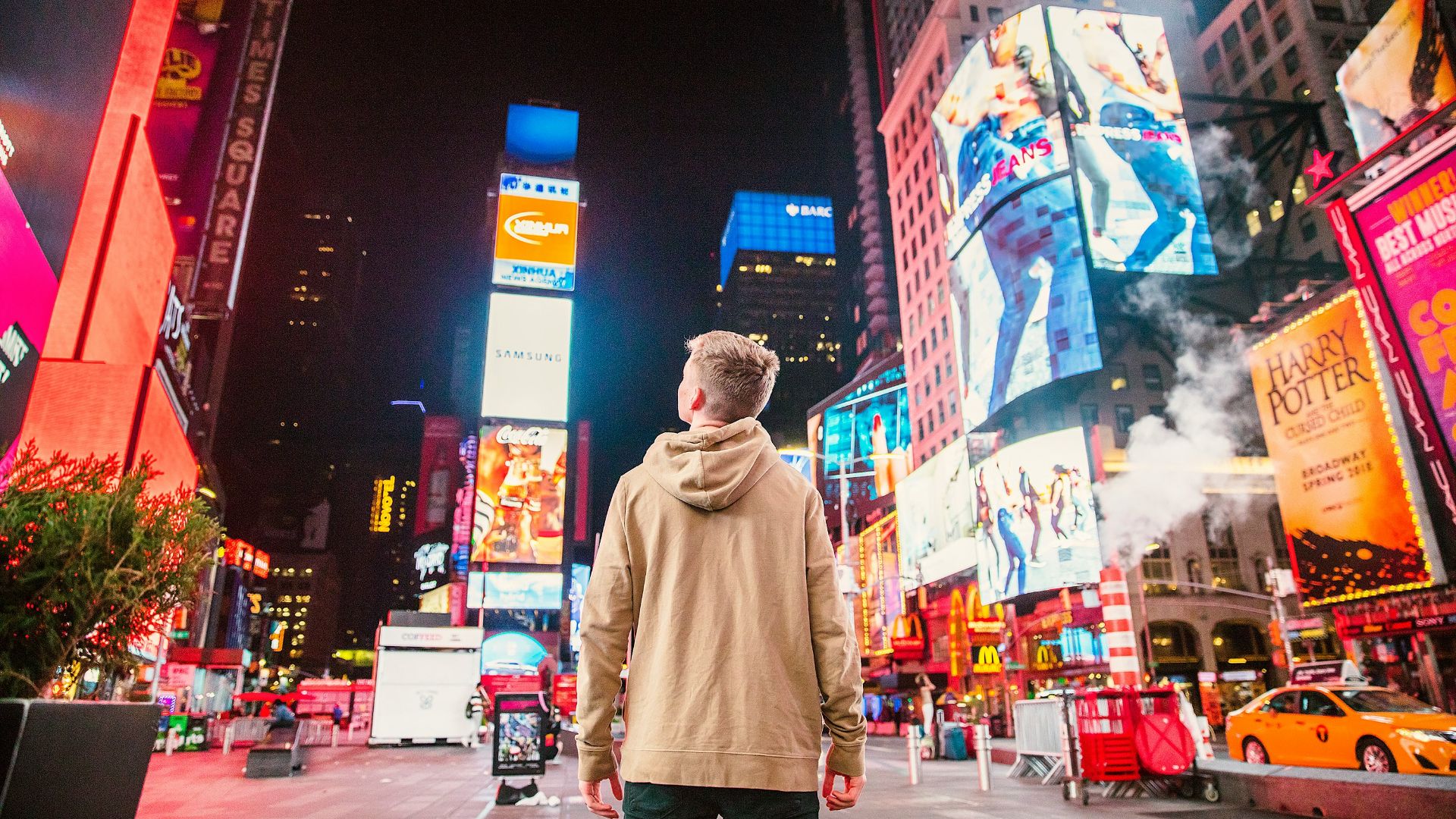 man standing on road infront of high-rise buildi
