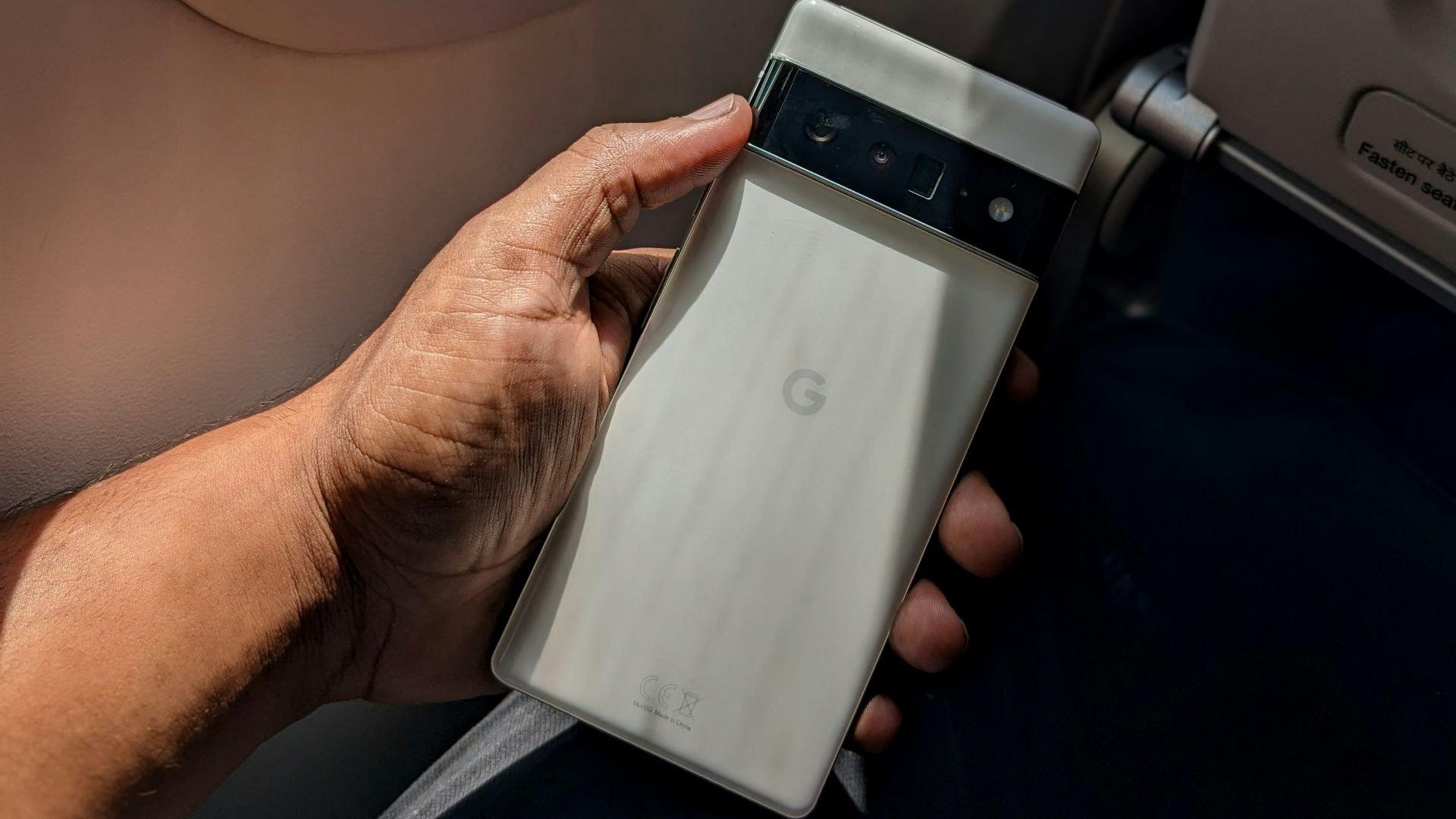 a person holding a cell phone next to an airplane window