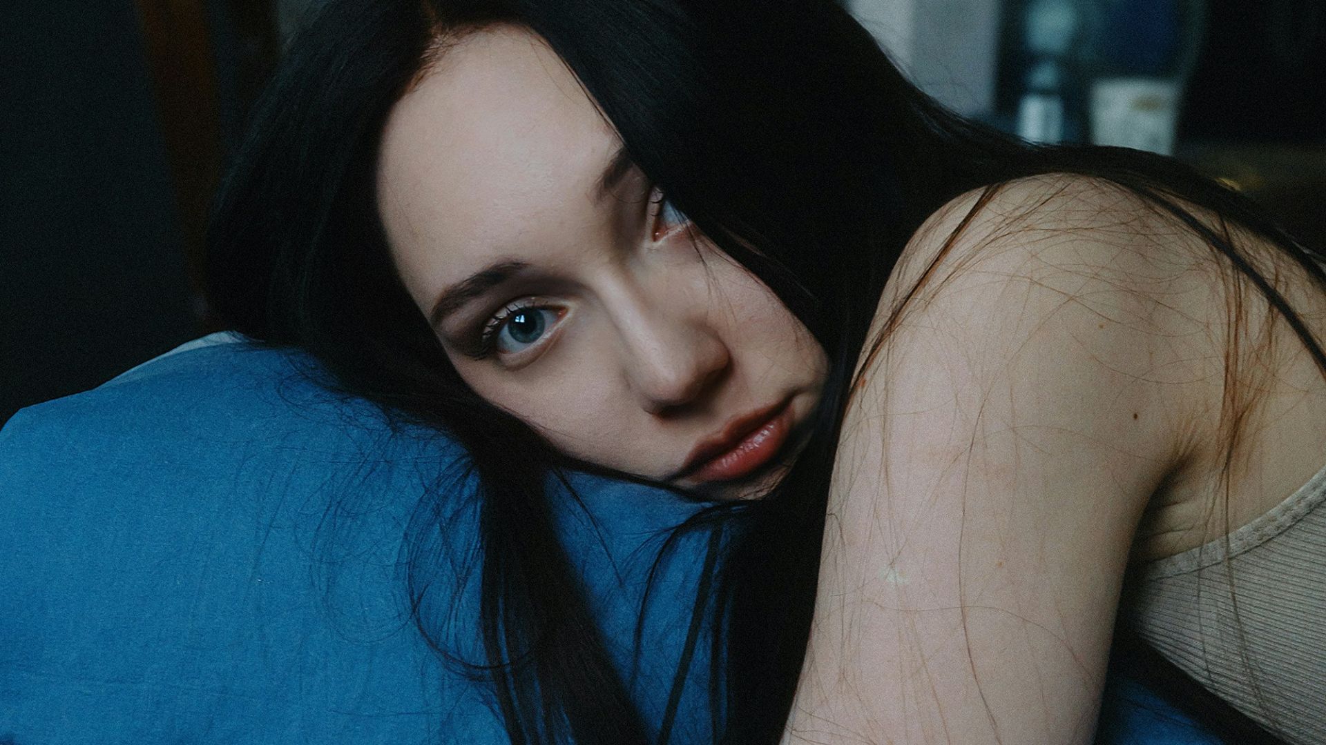 A woman laying in bed with a blue blanket