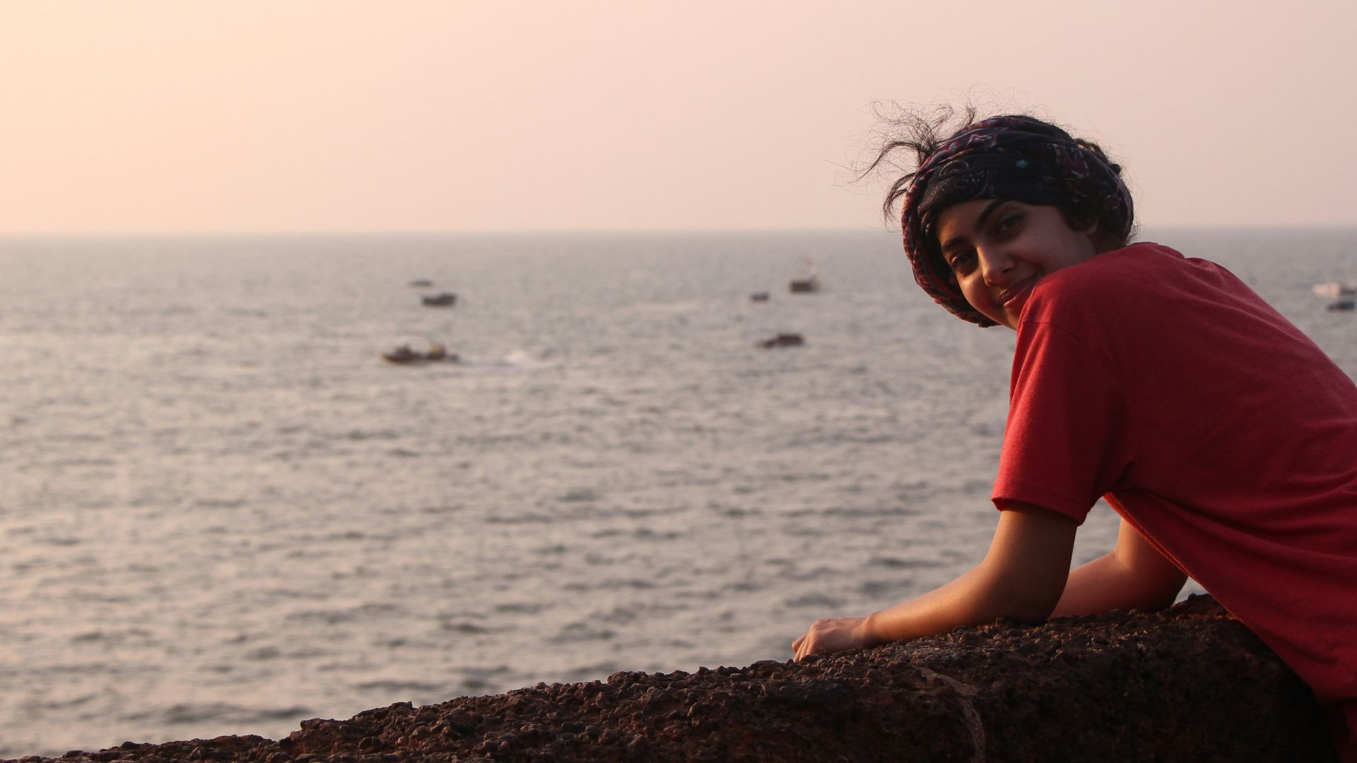 a woman leaning on a wall near the ocean