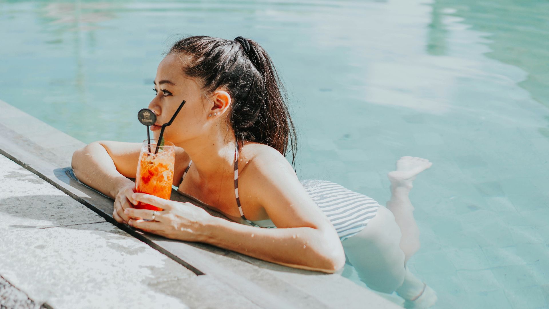 woman in white bikini drinking from orange juice