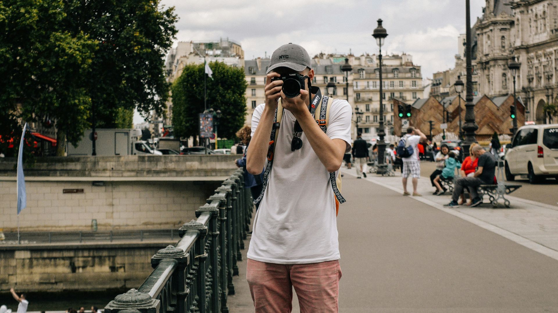man holding DSLR camera beside bridge