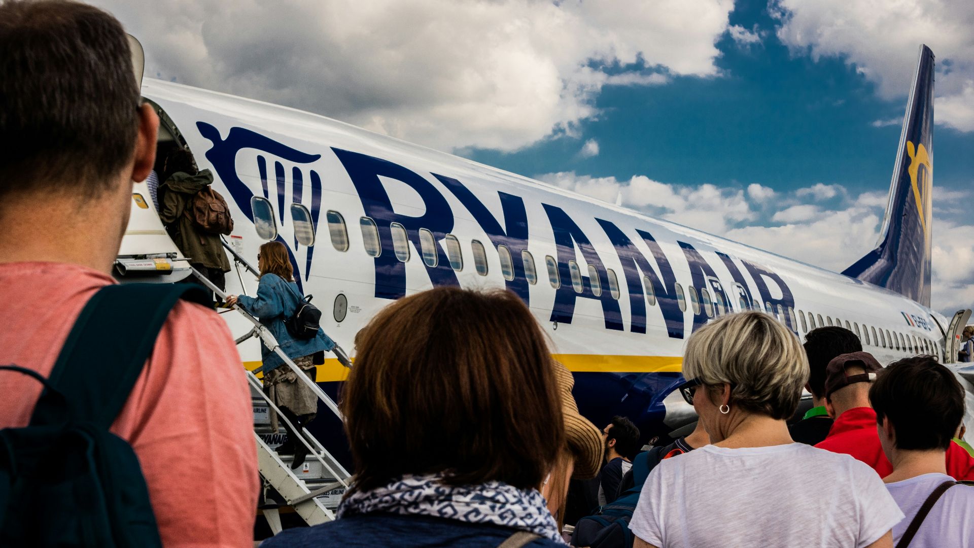 people sitting on chair near blue and white airplane under white clouds during daytime