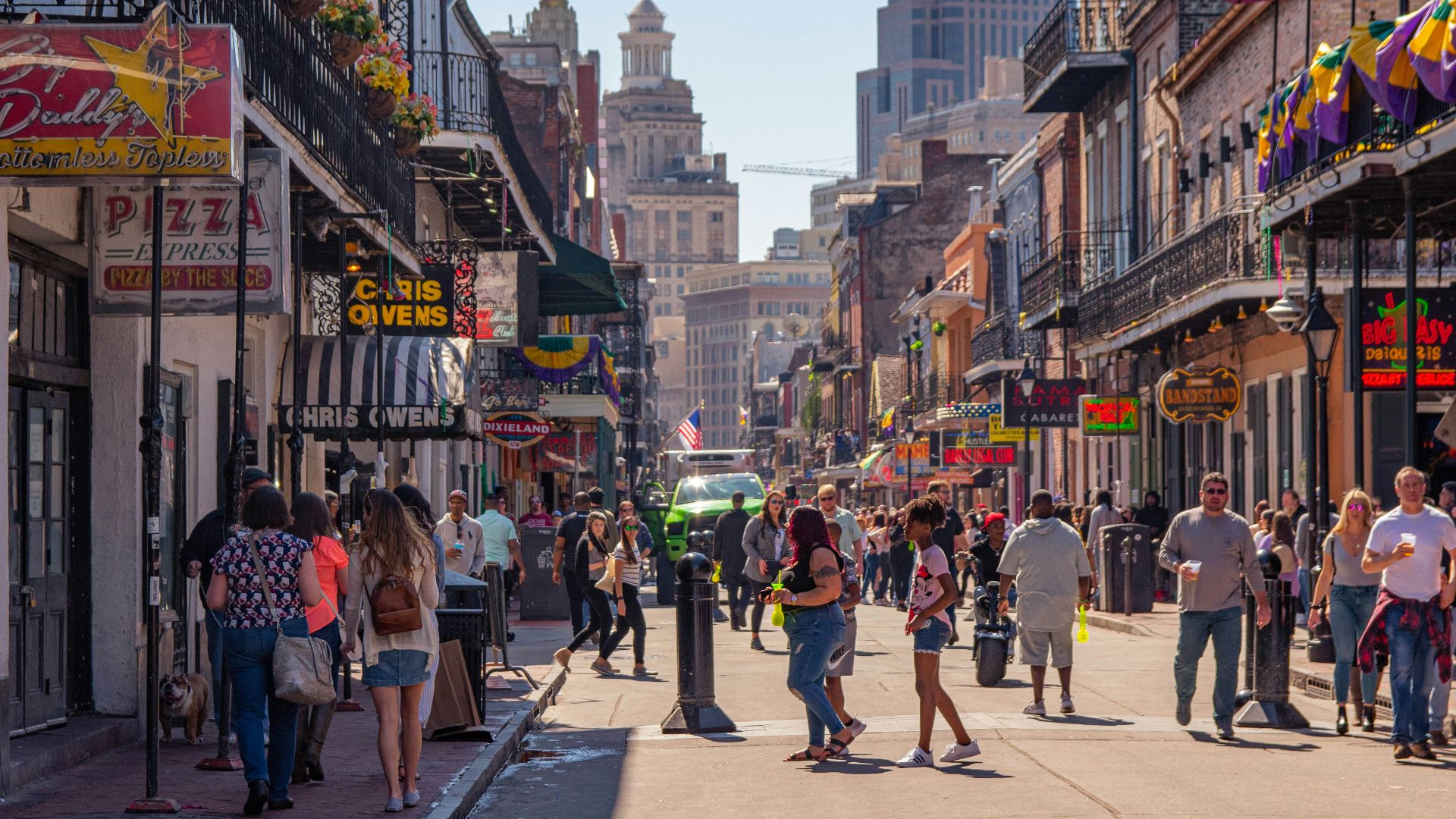 a group of people walking down a street next to tall buildings