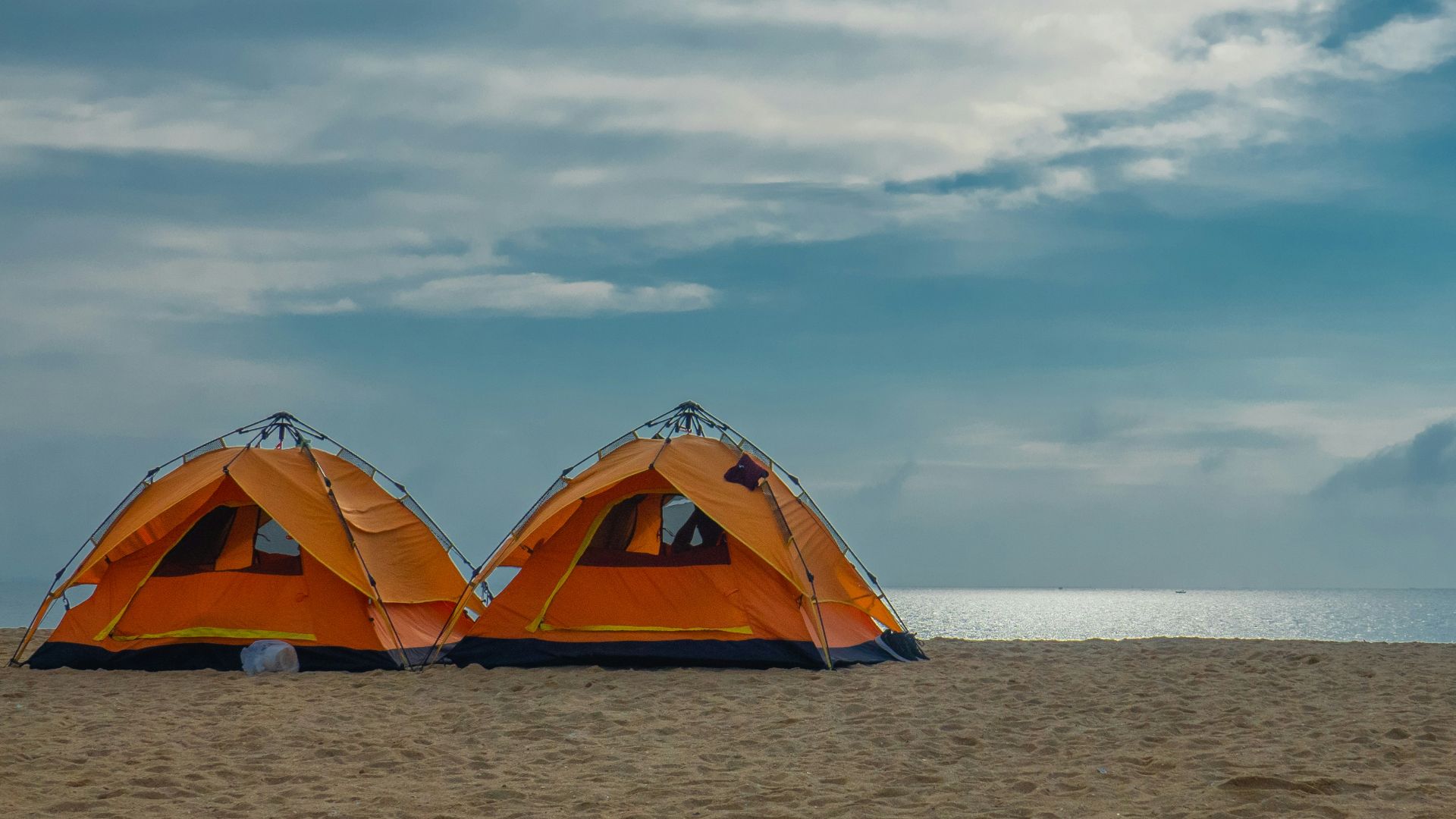 two orange and black tent at a beach