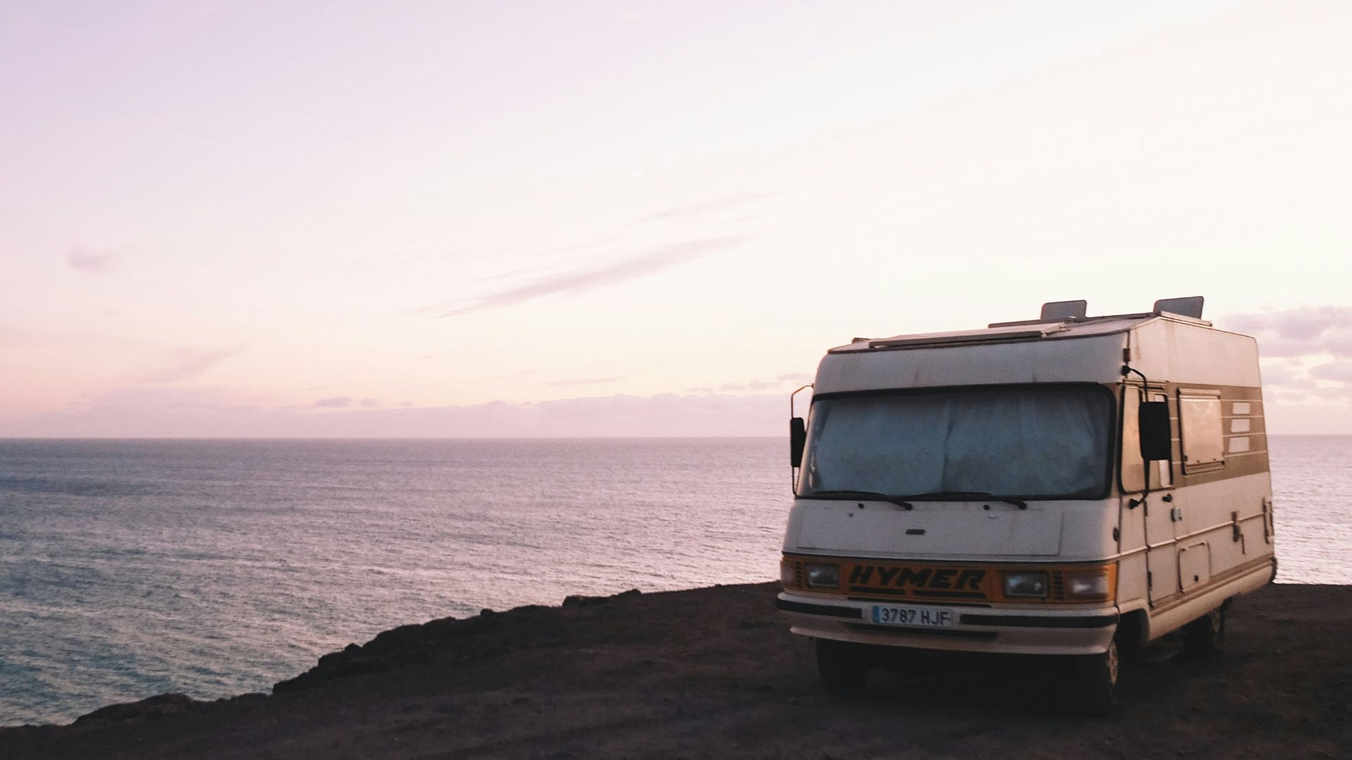 RV parked beside the edge of island during sunset
