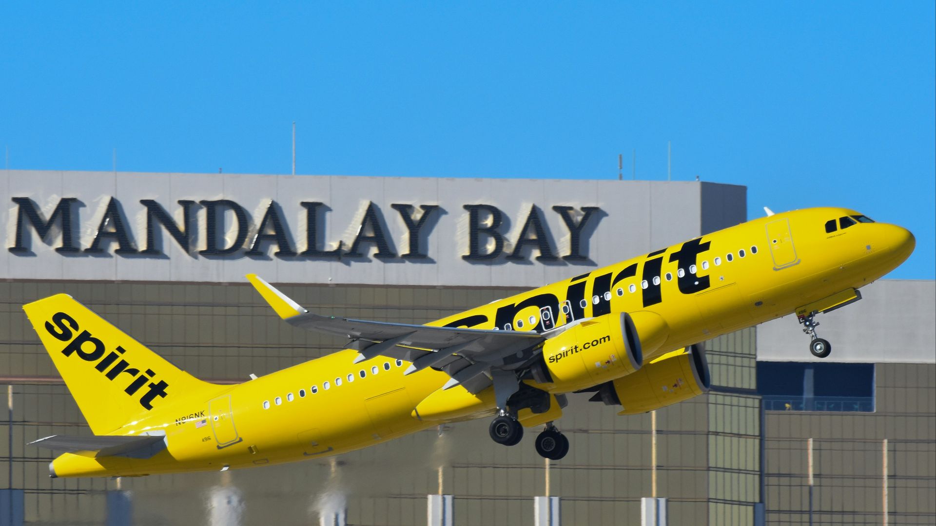 A yellow and black jet airliner taking off from an airport